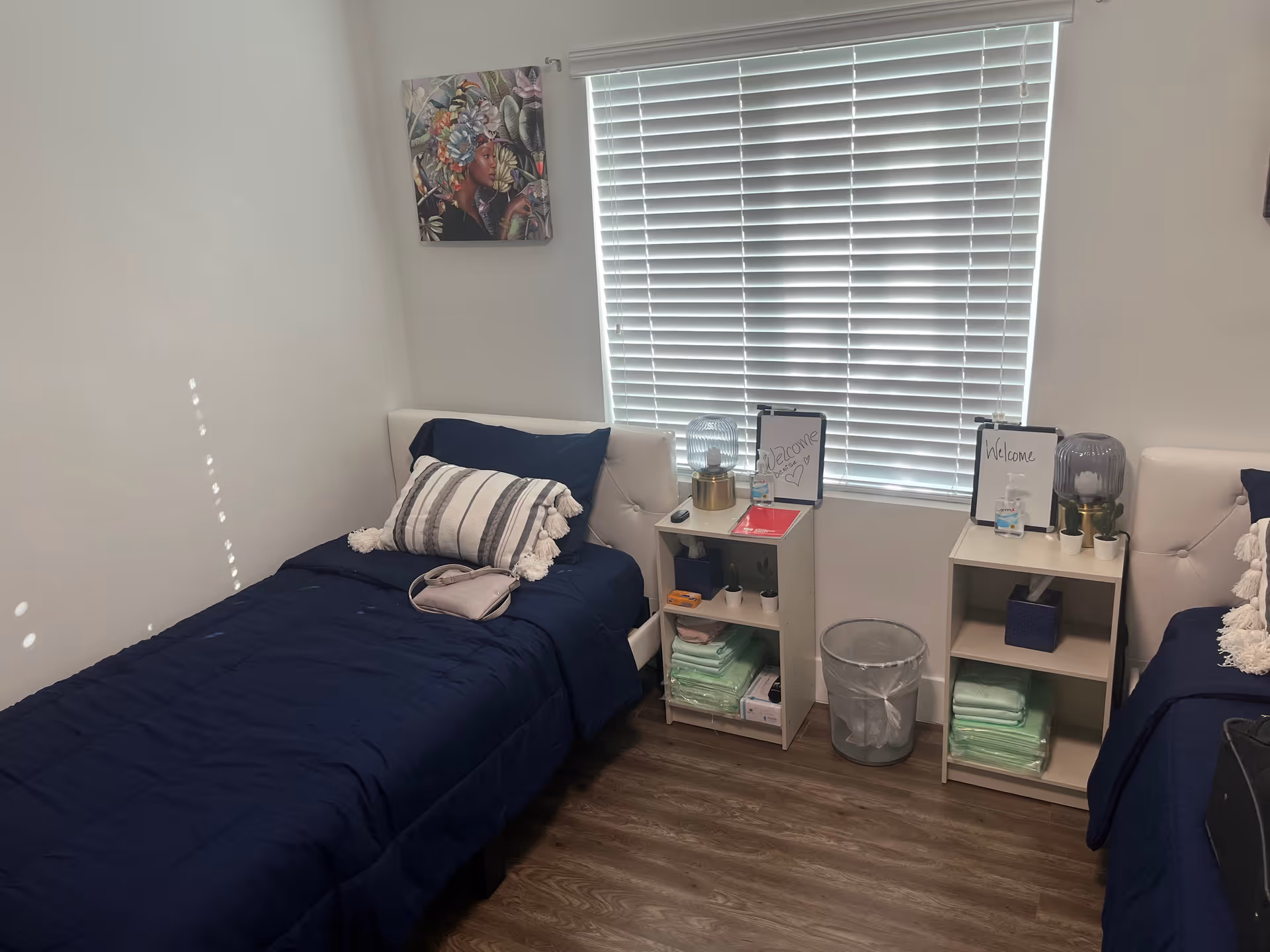 Two twin beds with navy bedding and nightstands by a large window.
