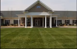 Bowling Green Senior Living front entrance with white columns and a well-manicured lawn.
