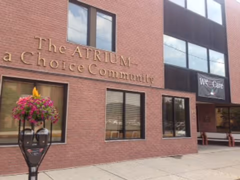 Brick exterior of The Atrium - A Choice Community with windows and a flower planter.