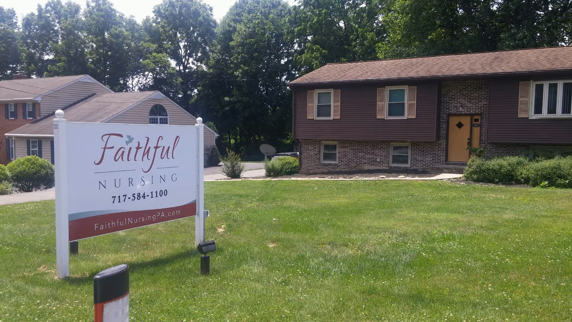 Front view of a Faithful Nursing facility with a large sign on a grassy lawn