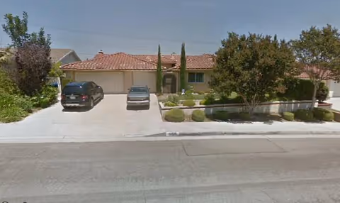 Exterior view of Monaco Crest Guest Home with driveway and parked cars.