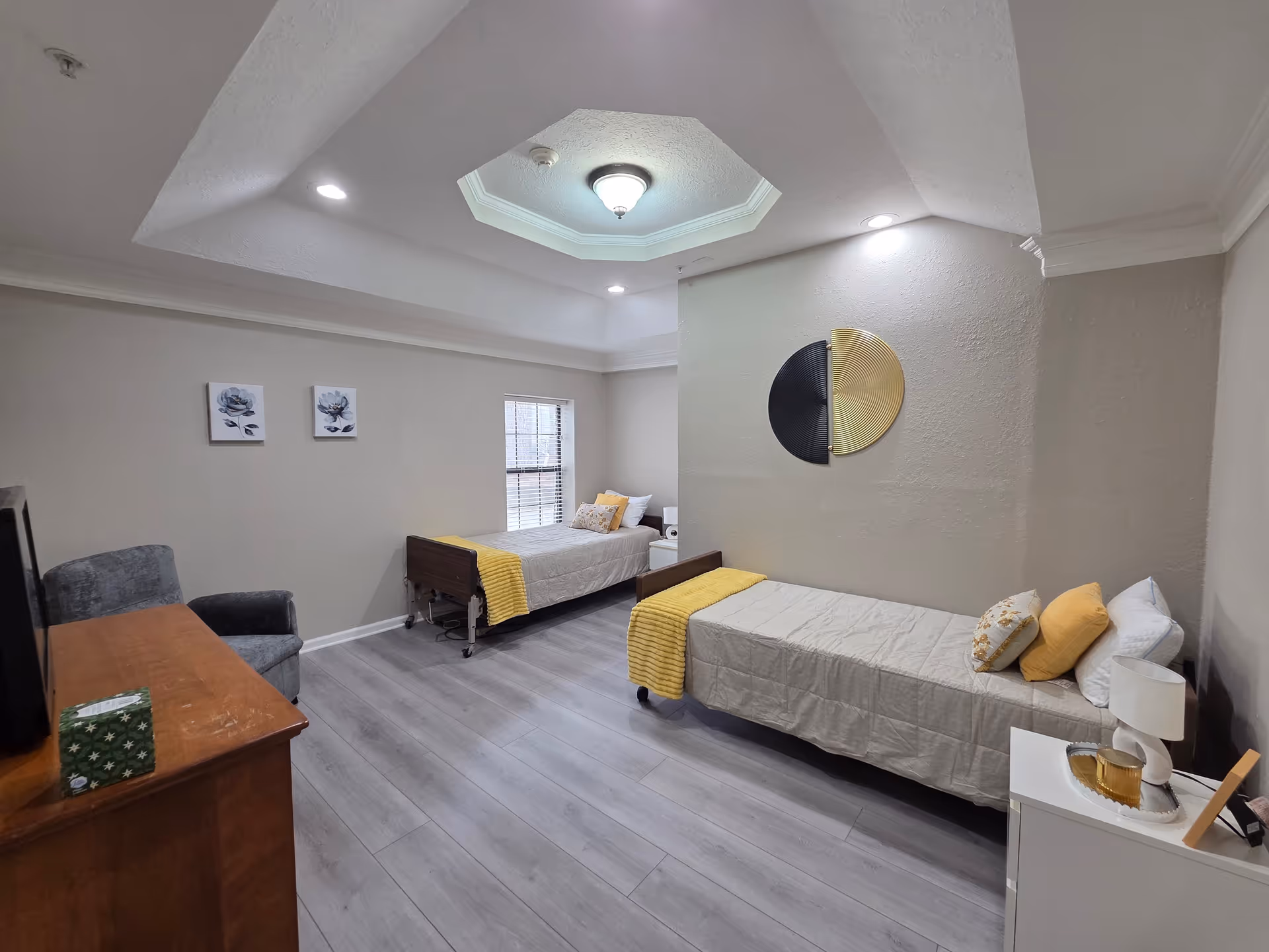 Shared bedroom in Sunrise Senior Care Home with two beds and yellow accents.
