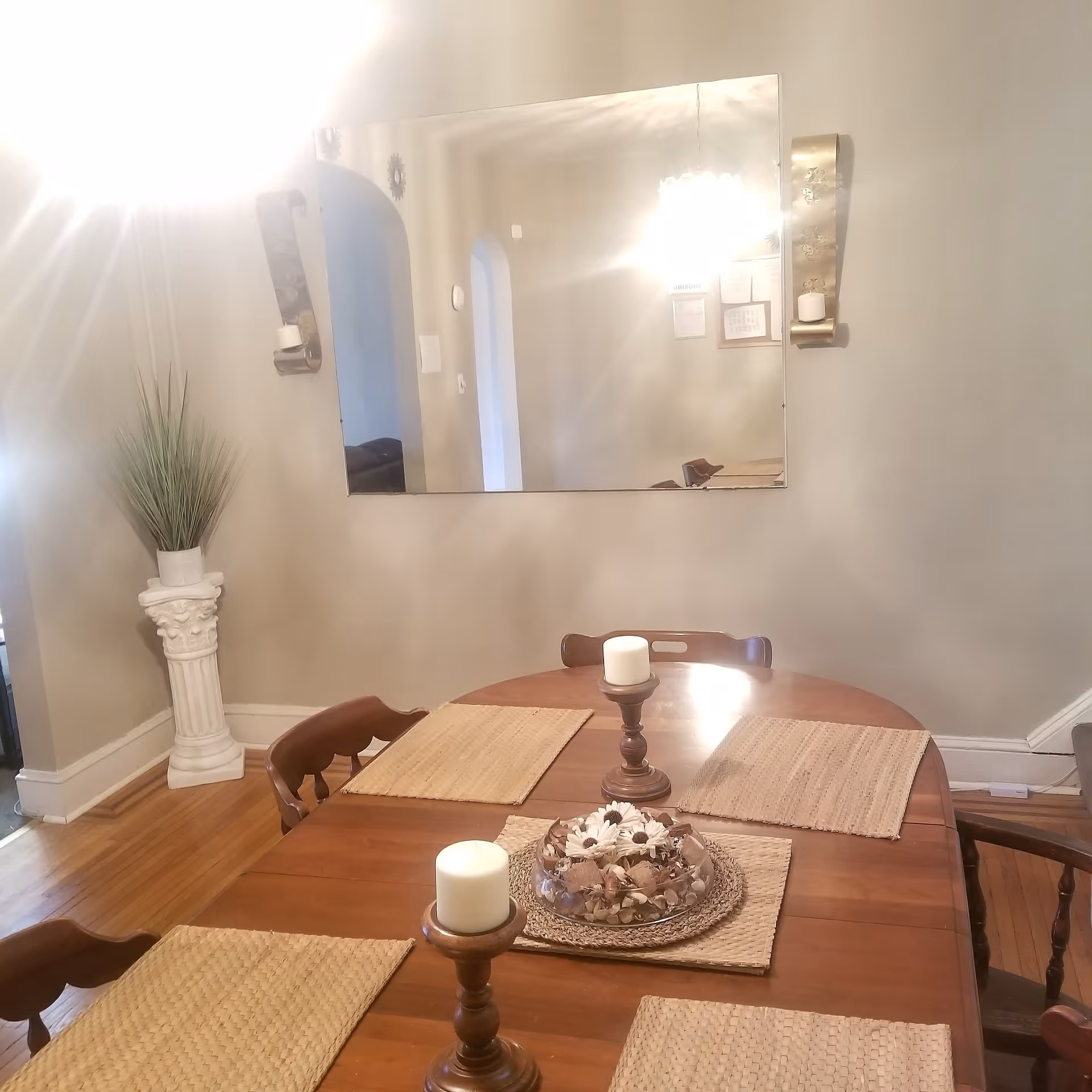 Dining room with a wooden table, placemats, candles, and a wall mirror.