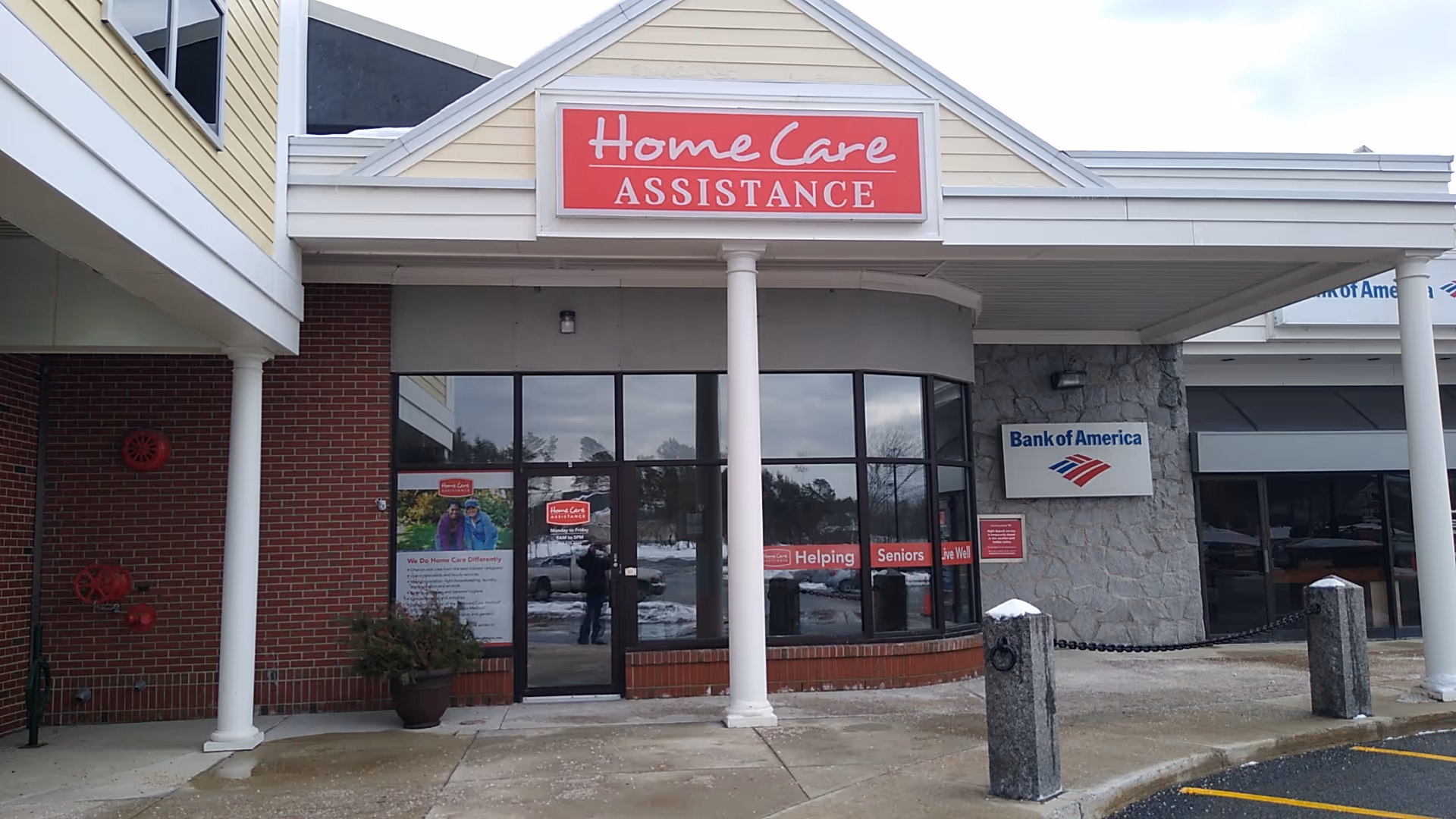 Exterior storefront with Home Care Assistance signage beside Bank of America.