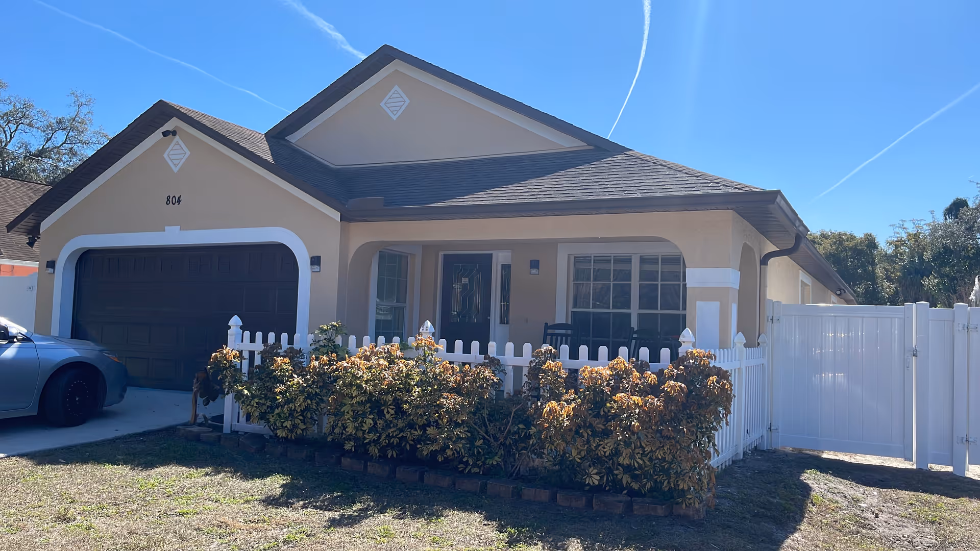 Bella Rose ALF front exterior, a single-story beige facility with a white fence and shrubs.
