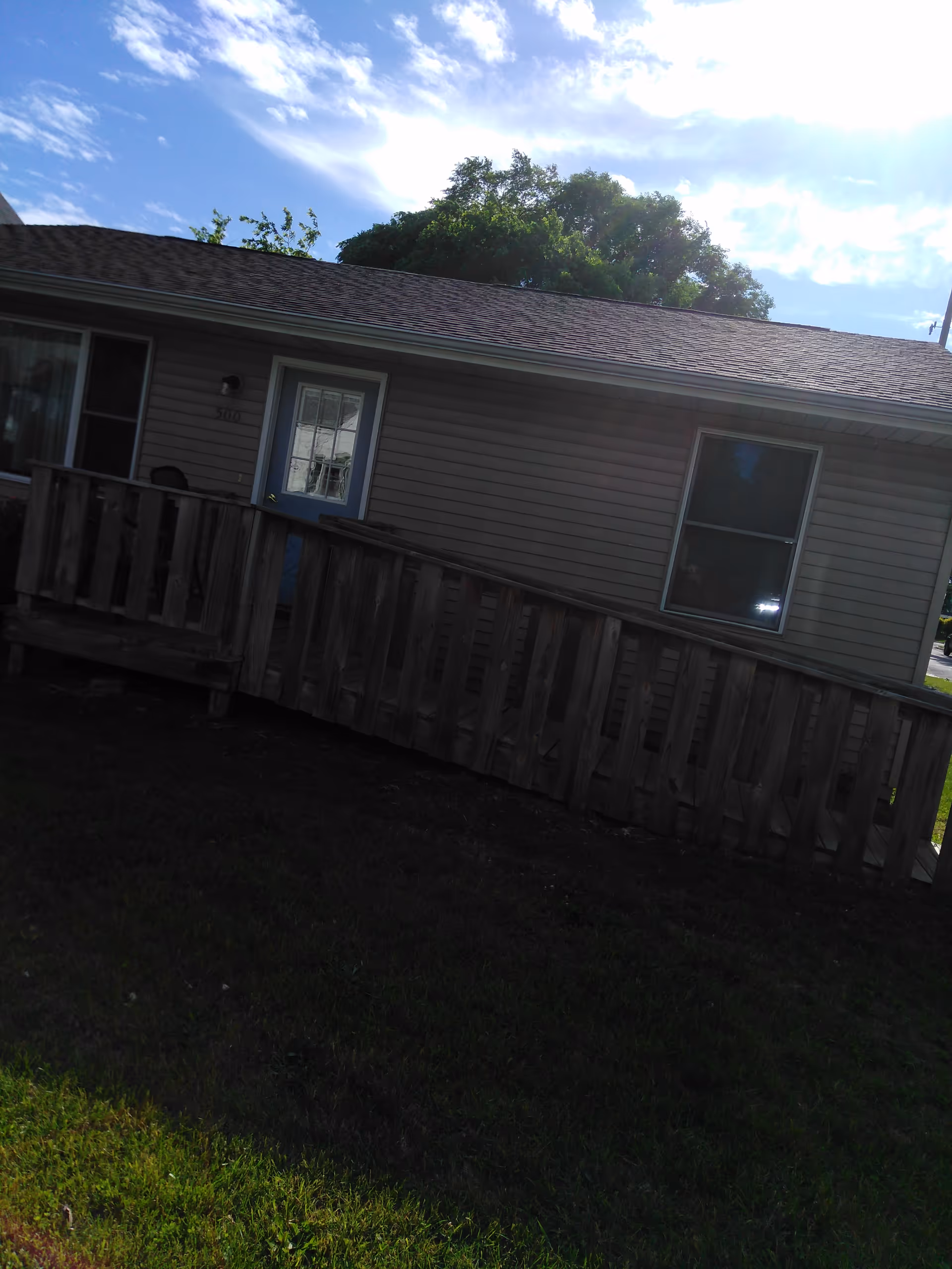 Exterior view of a beige modular home with a wooden railing and front porch.