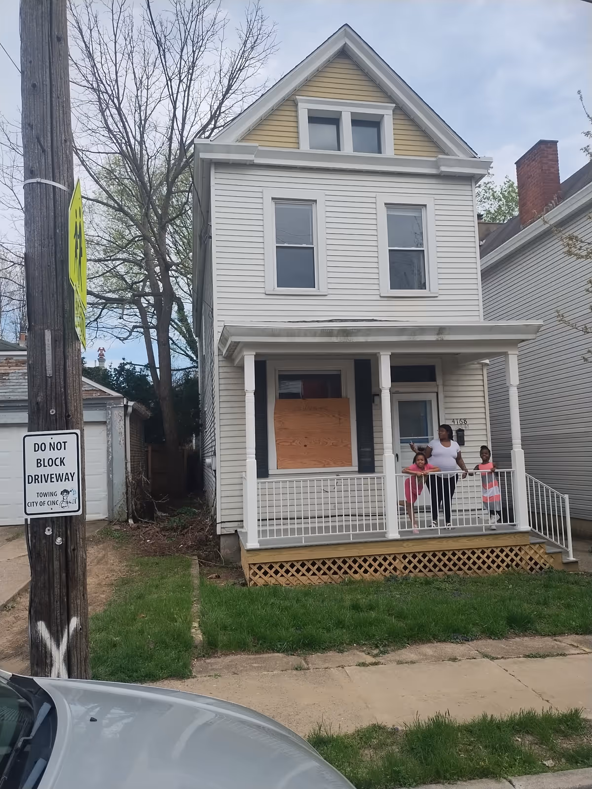 Two-story white house with a front porch and four people on the porch.