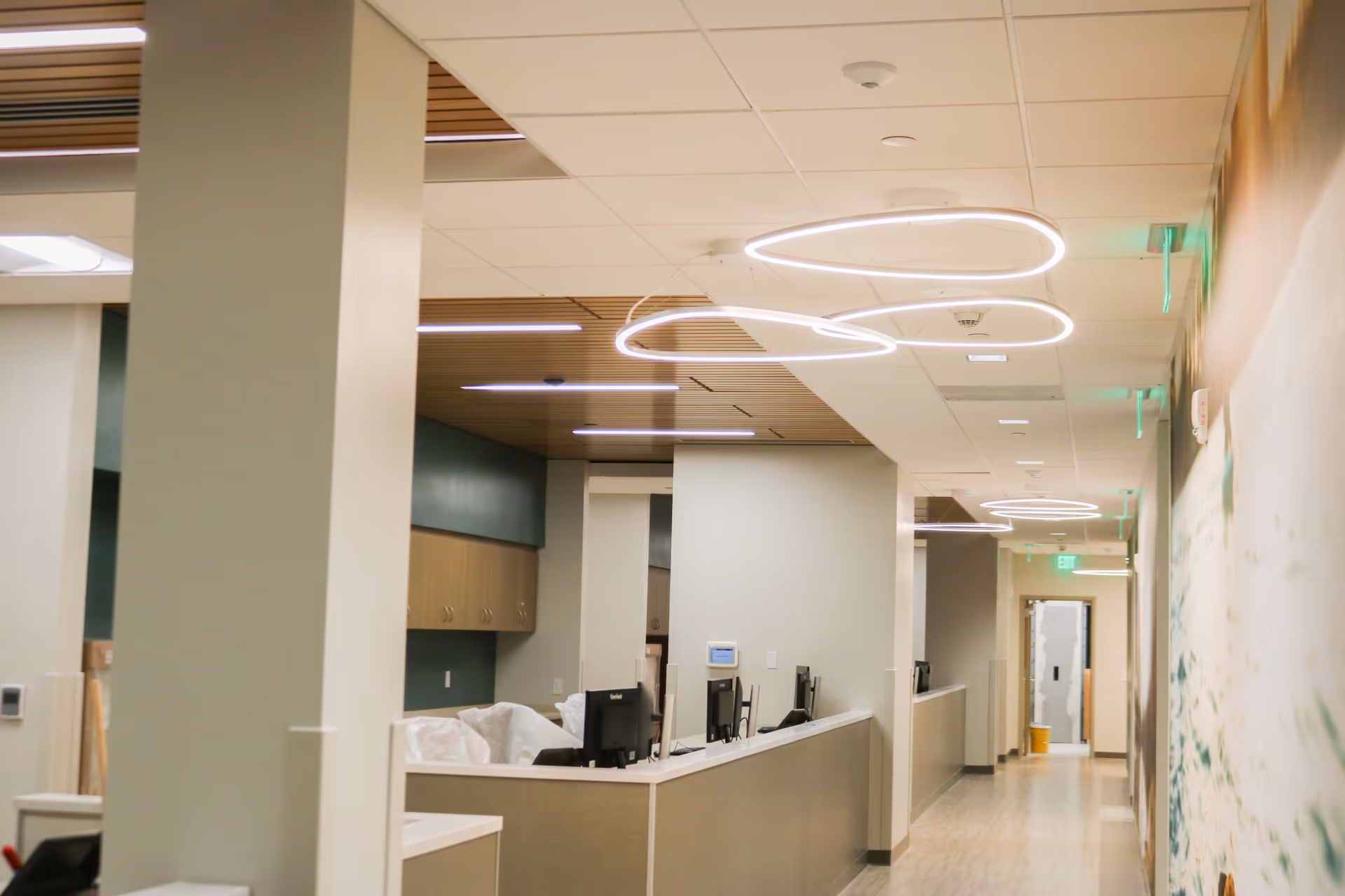 Interior hallway of a senior living facility with a reception desk and circular ceiling lights.