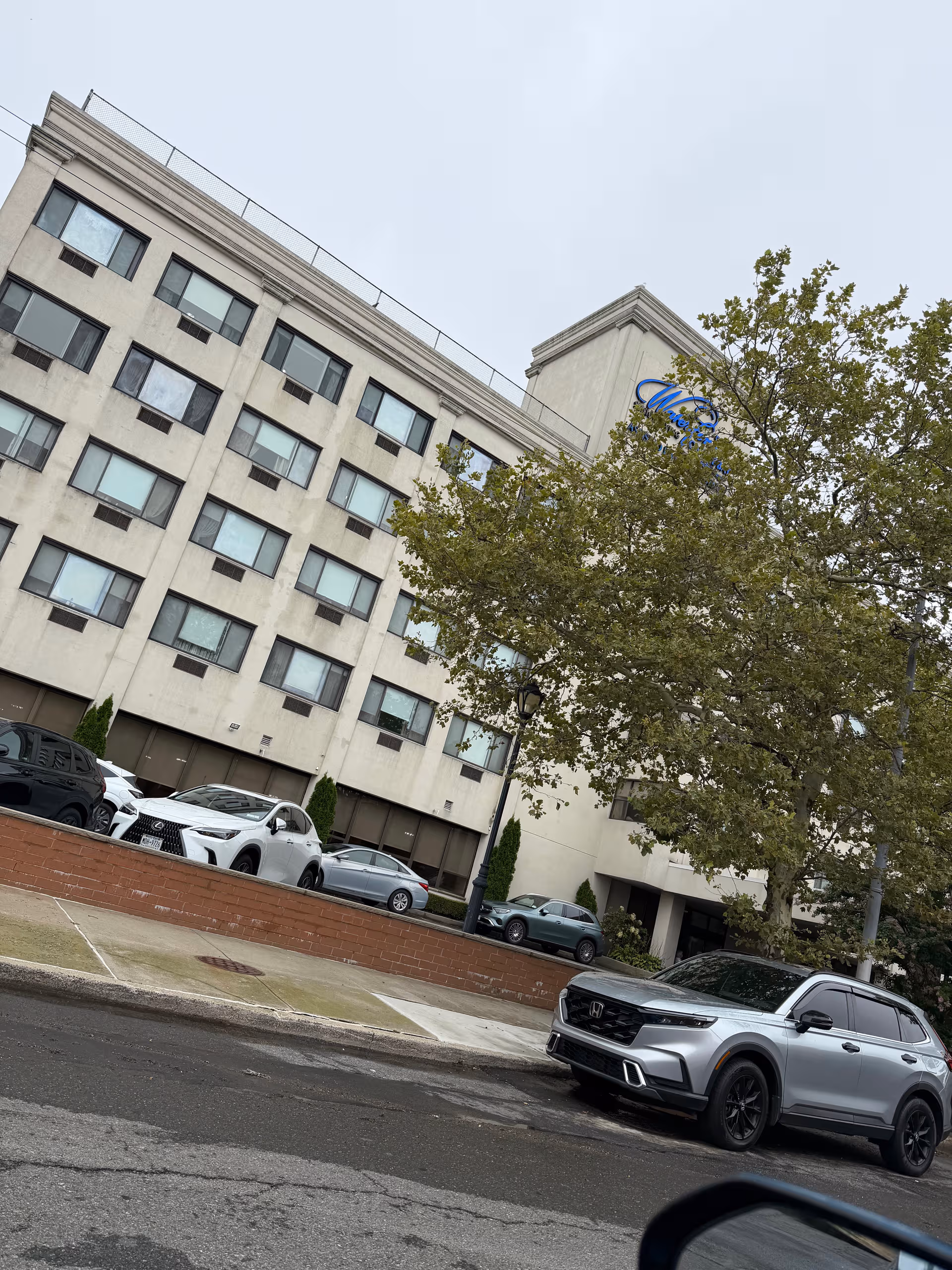 Exterior view of The Waterford on the Bay Senior Living building with parked cars.