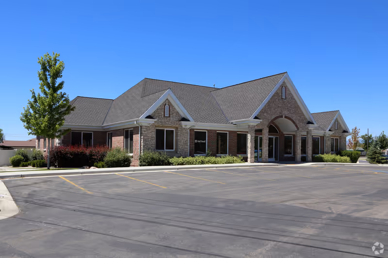 Exterior view of a single-story brick and stone building with an arched entrance and parking.