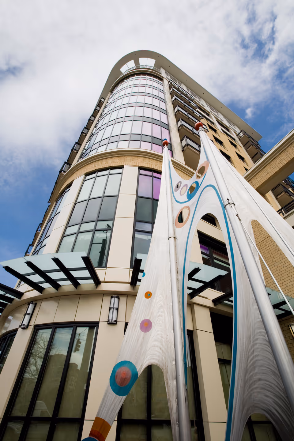 Tall modern Mirabella Seattle exterior with a curved, colorful sculpture in the foreground.