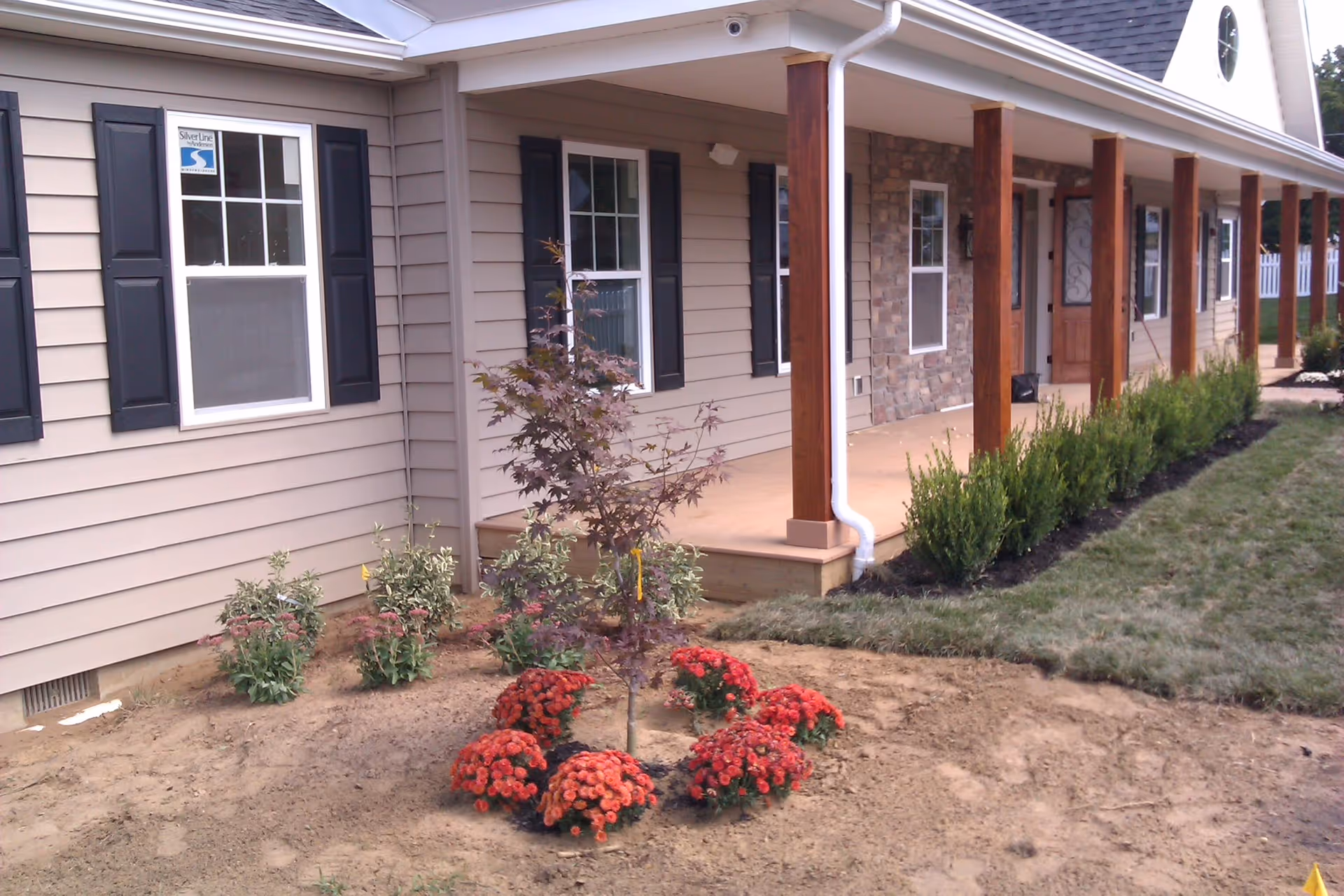 Exterior of a senior living facility with a covered porch and landscaped front yard.