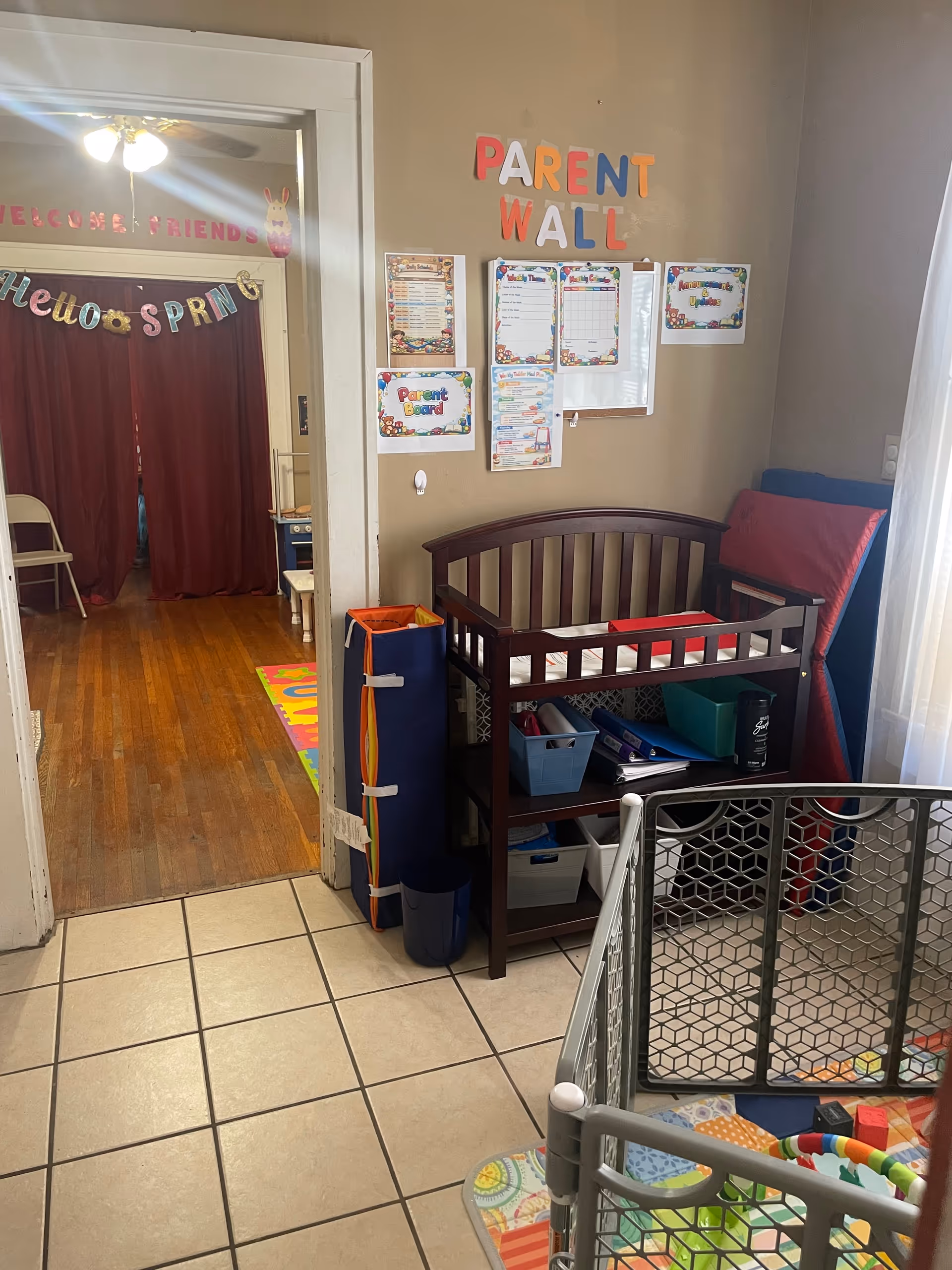 Interior view of a small activity area with a wooden baby crib and organized bins.