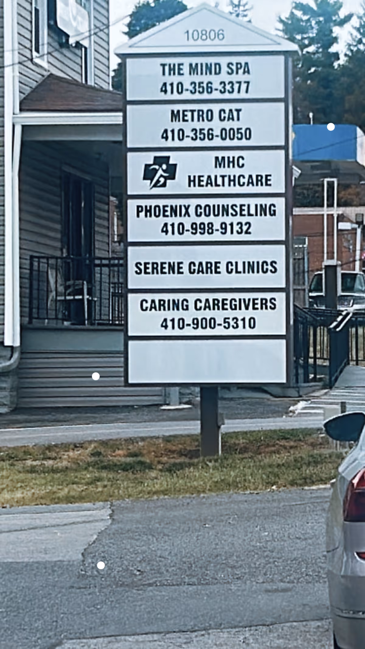 Outdoor signboard listing Caring Caregivers Staffing Agency and other services beside a building.