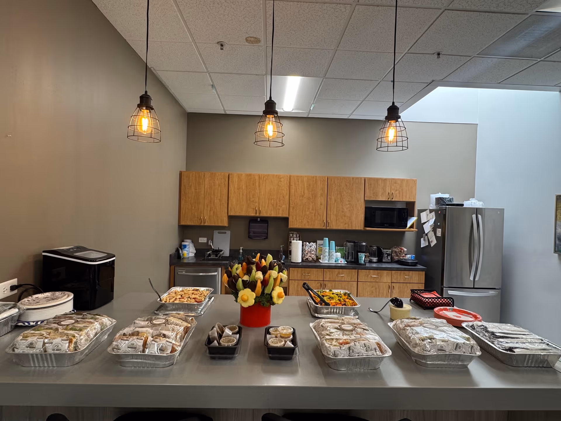 Buffet-style trays of food on a long counter in a communal kitchen.
