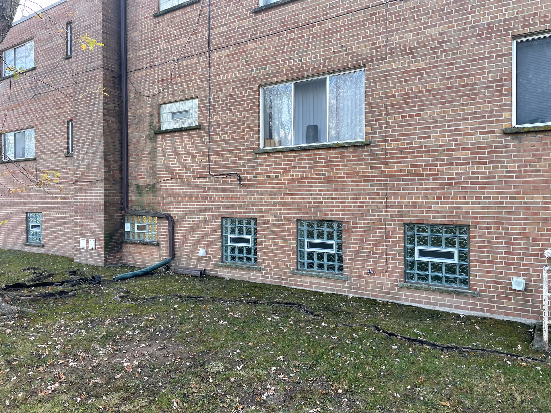 Brick exterior of a multi-story senior living building with pipes along the wall.