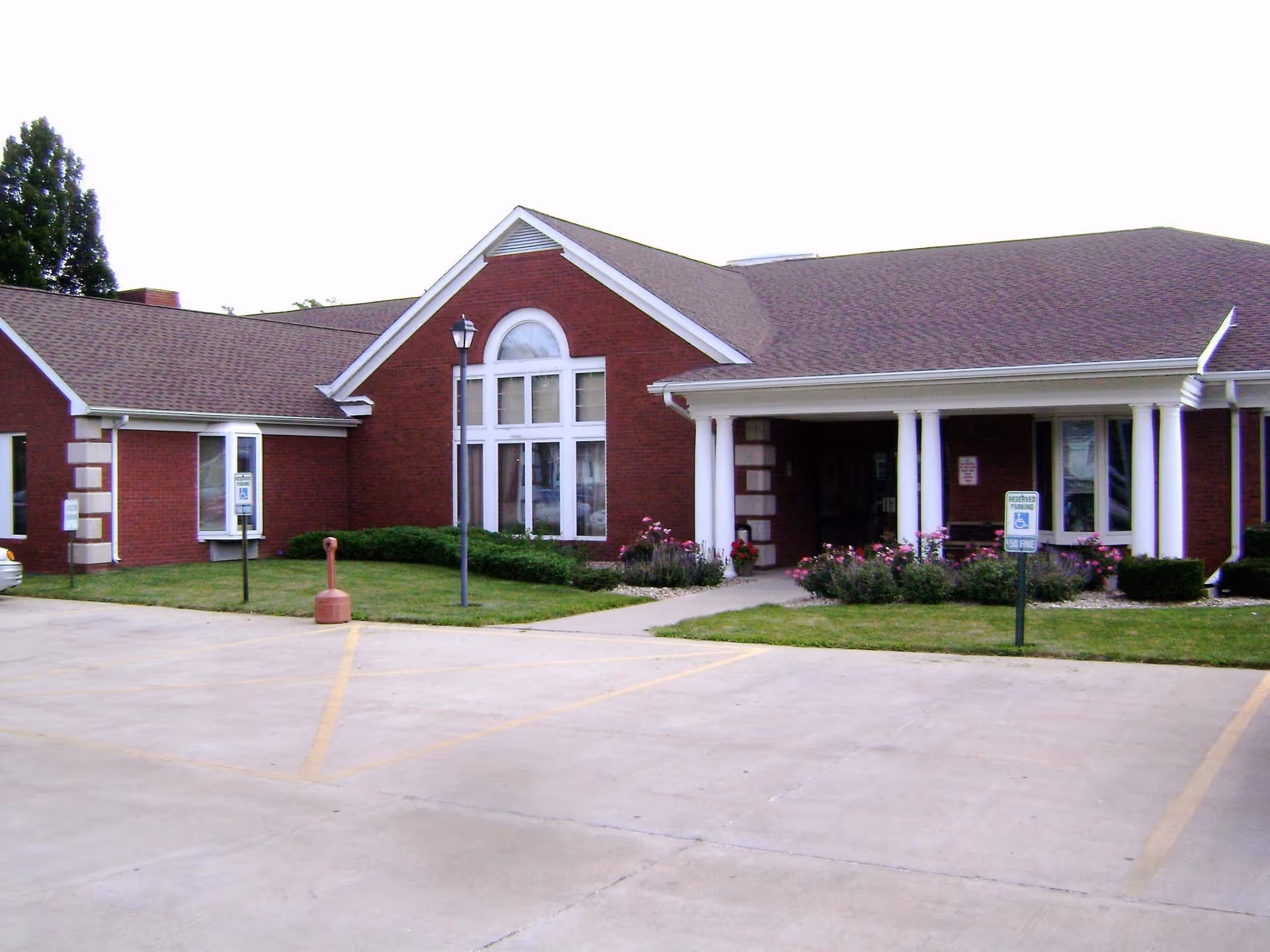 Exterior view of Leroy Manor senior living facility with brick facade and landscaped entry.