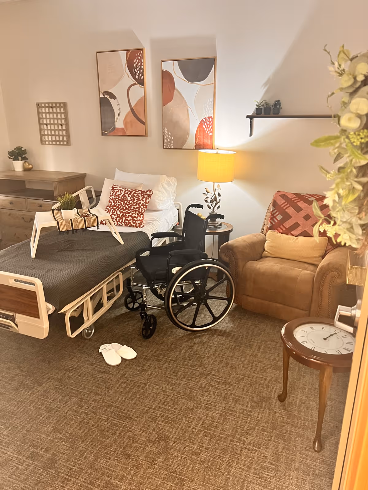 Senior living room with a hospital bed, wheelchair, sofa, and decorative art.