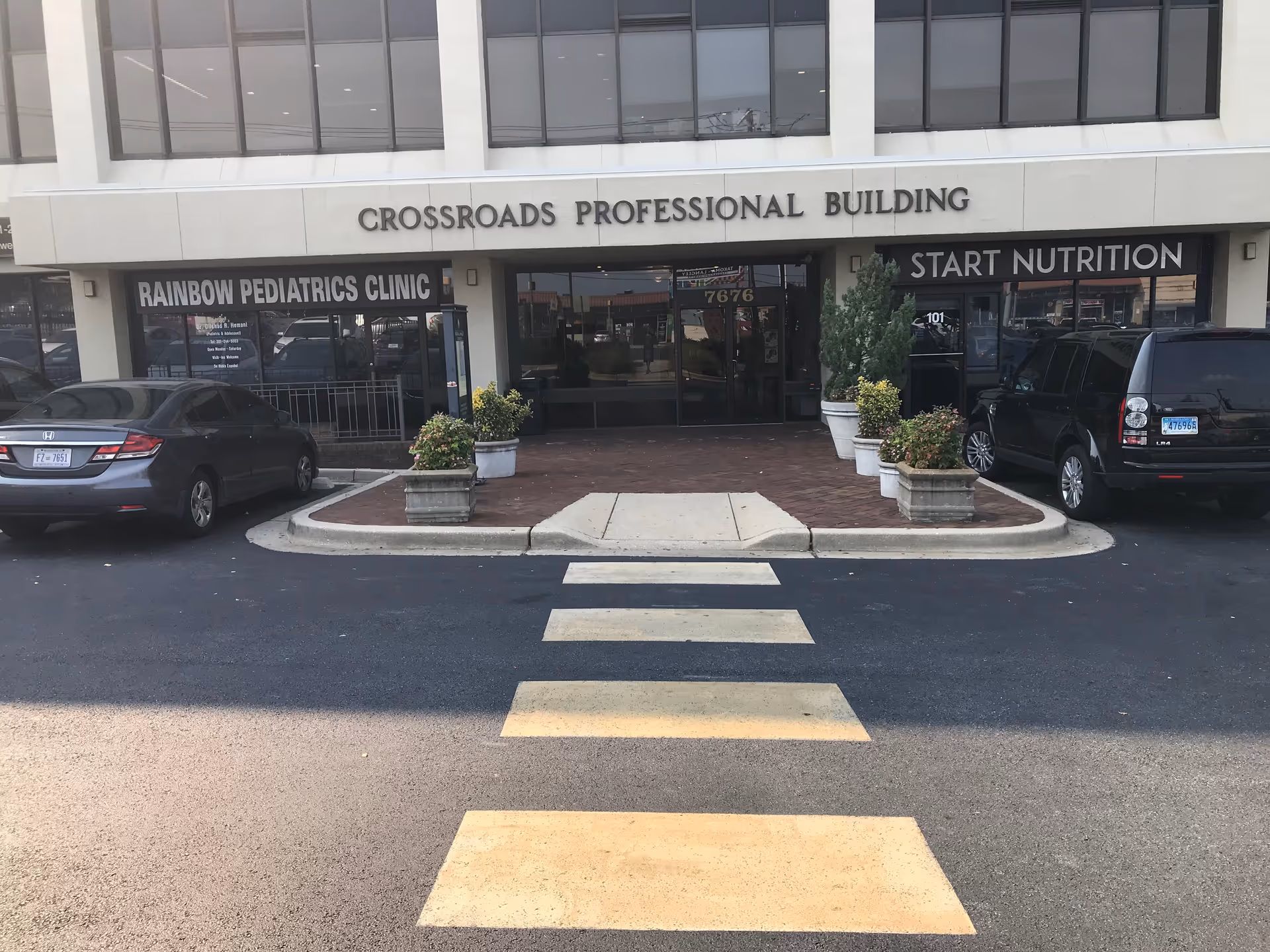 Front view of Crossroads Professional Building with clinic storefronts and a crosswalk.