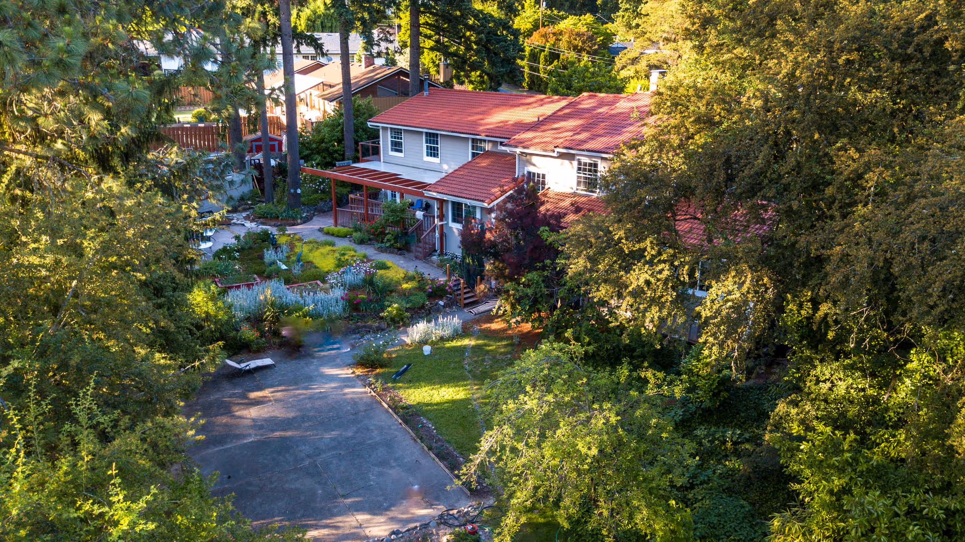 A red-roofed senior living house surrounded by trees and a landscaped front yard.