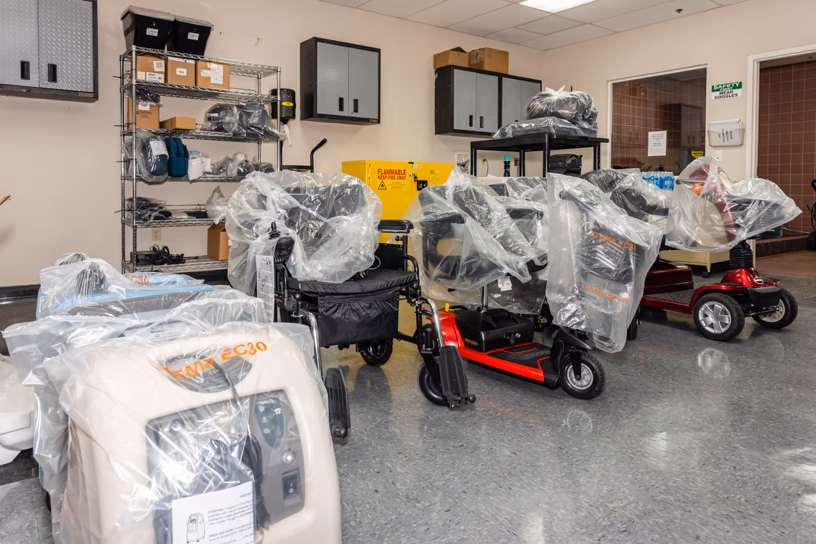 A storage room with plastic-covered mobility scooters and shelves of supplies.