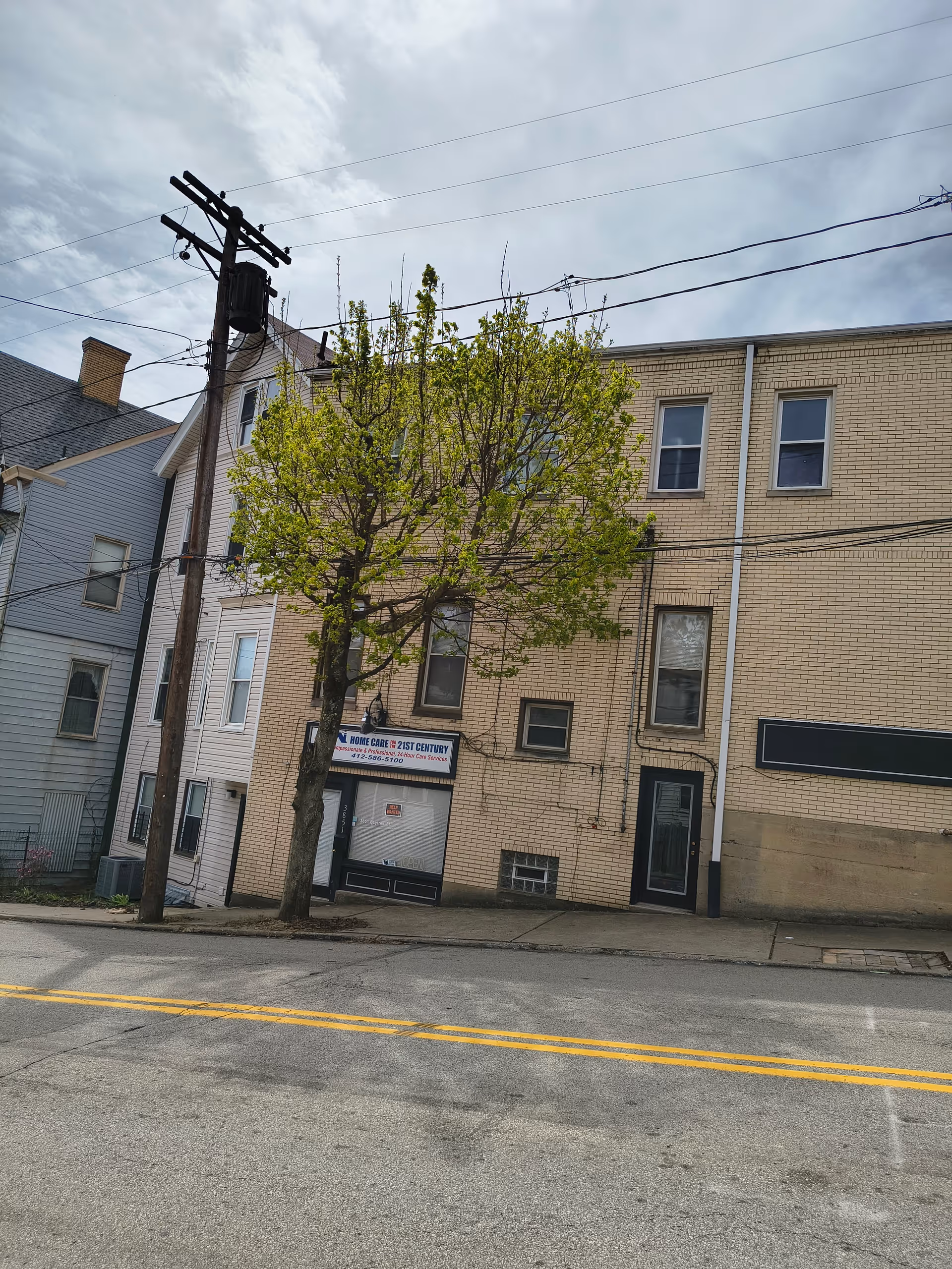 Front view of a brick building with storefront signs along a residential street
