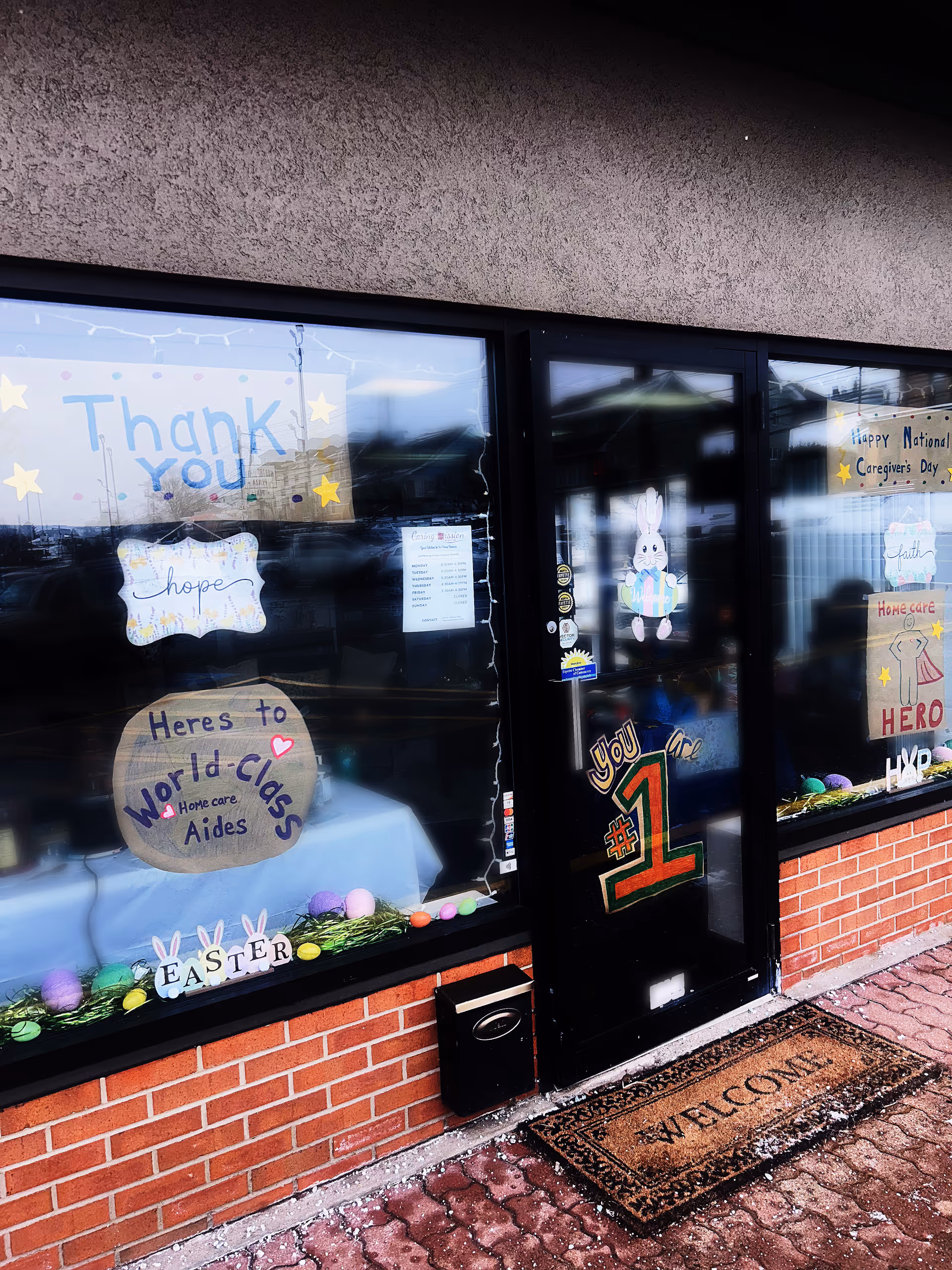 Storefront of Caring Mission Home Care with Easter decorations and welcome signs in windows and door.