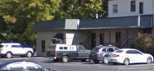 Front view of a building with several parked cars in a parking lot