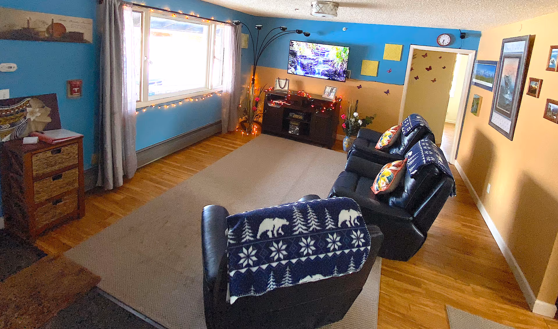 Cozy living room in a senior facility with recliners, a TV, two-tone walls, and a window.