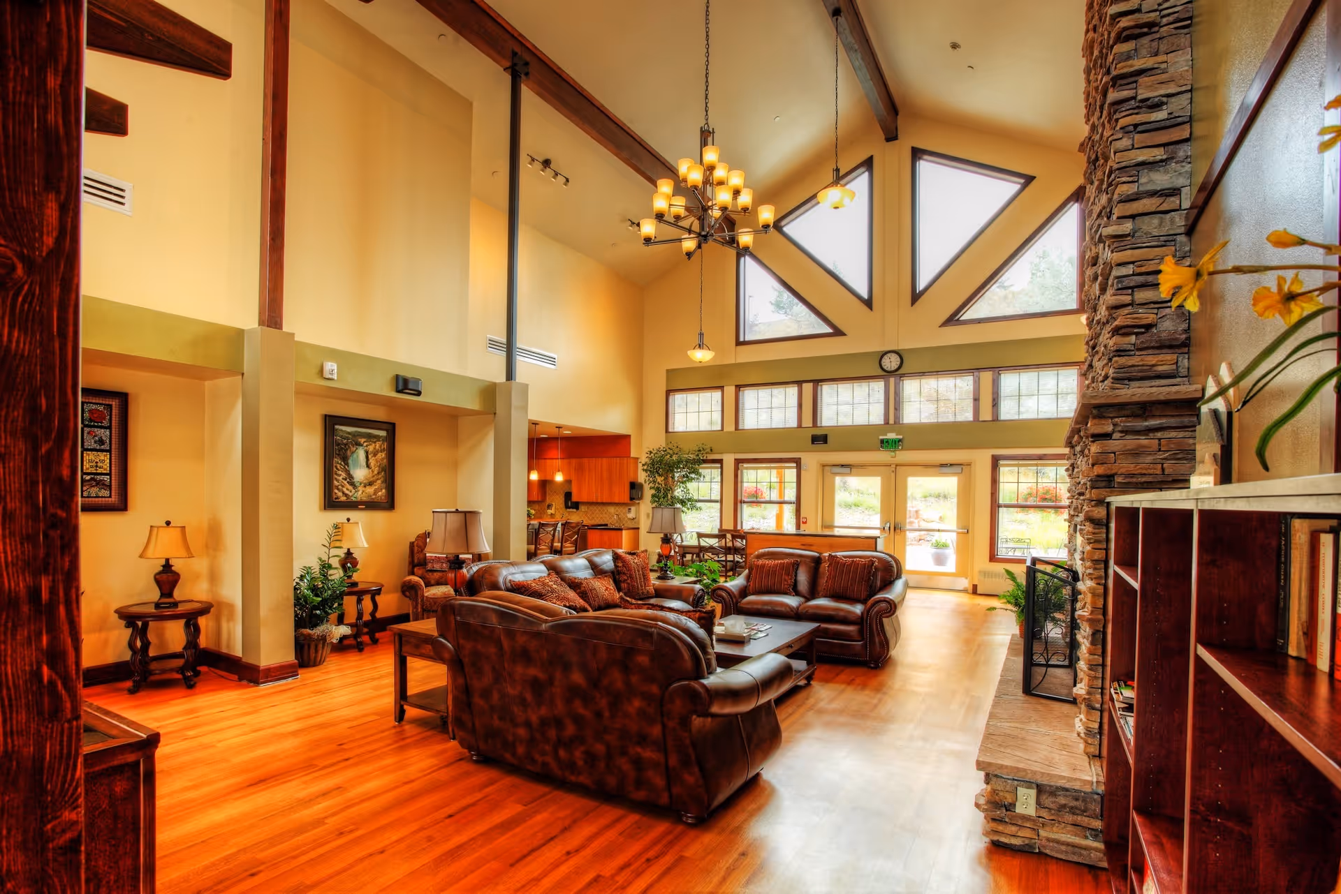 Spacious living room in a senior facility with leather seating and a stone fireplace.