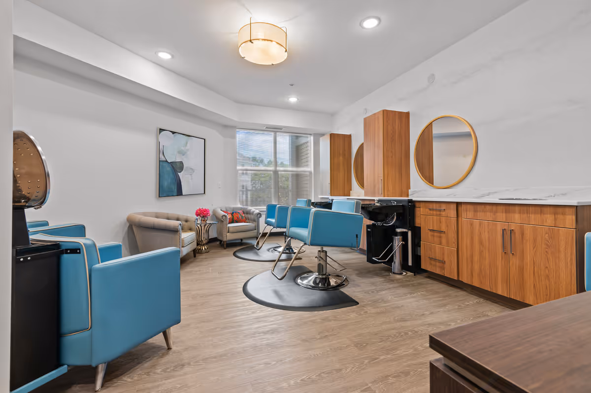 A modern salon with blue chairs, mirrors, and wooden cabinetry in a senior living facility.