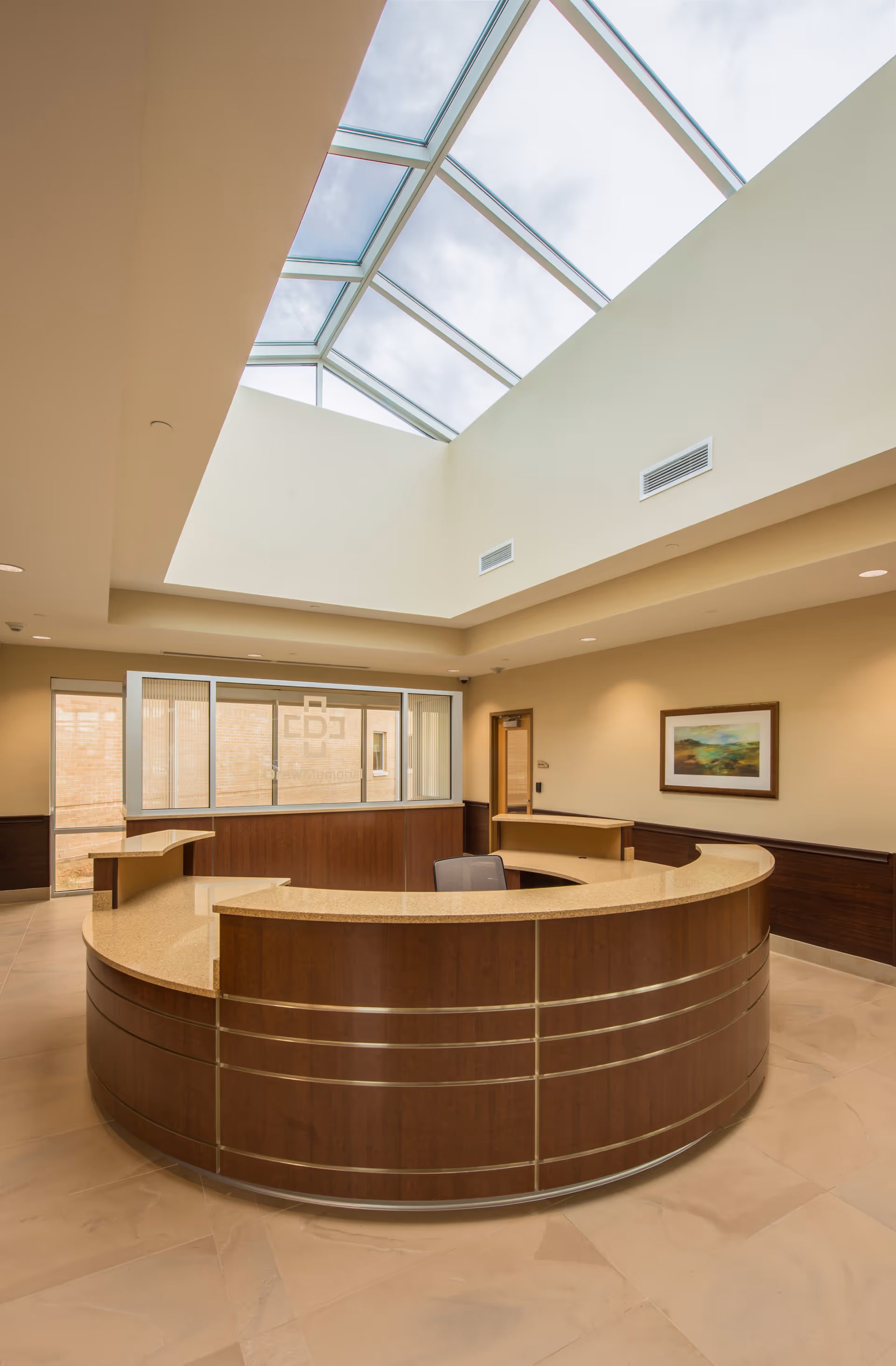 Curved wooden reception desk in a bright lobby with a skylight overhead.