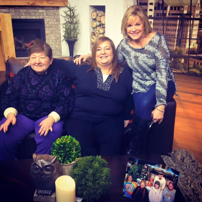 Three smiling women sit on a couch in a living room at Homewatch CareGivers of Columbus.