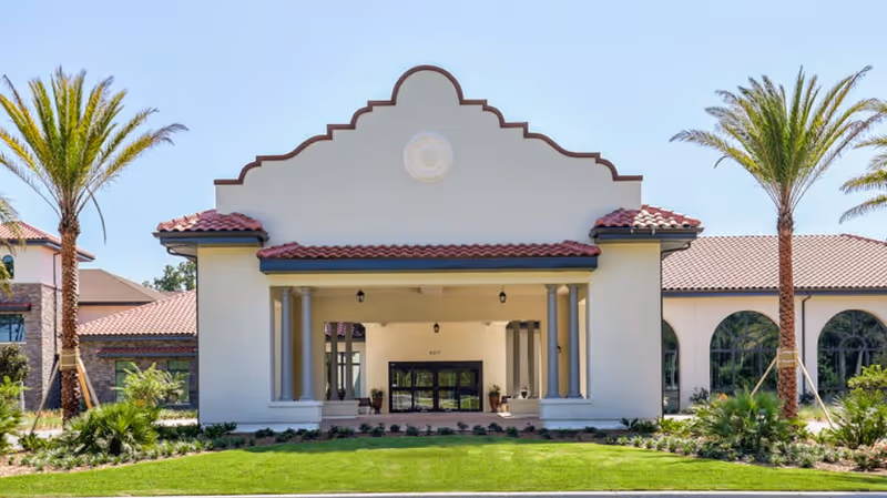 Front entrance of Magnolia Ridge Rehabilitation Center with columns, red-tiled roof, and palm trees.