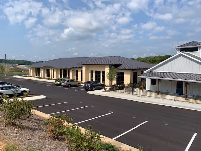 Exterior view of a single-story senior living facility with a paved parking lot.