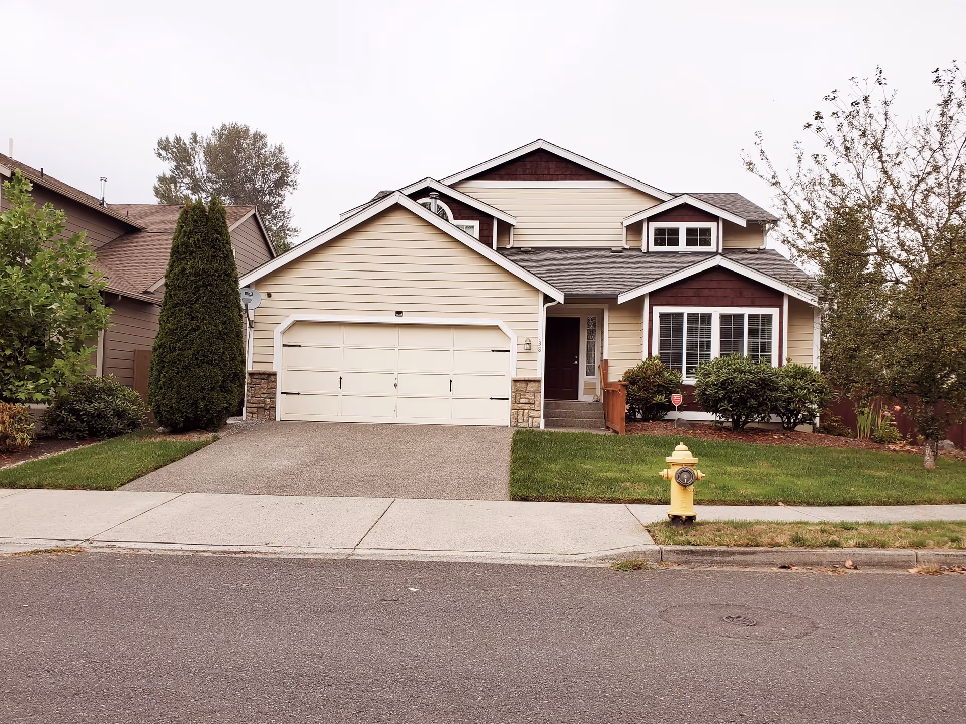 Front exterior of a beige suburban house with a two-car garage.