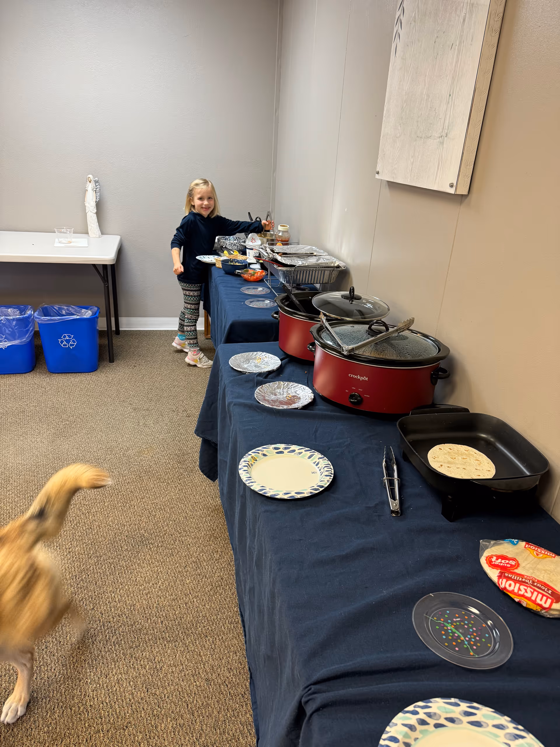 Young girl stands at a buffet table in a senior living facility dining room.