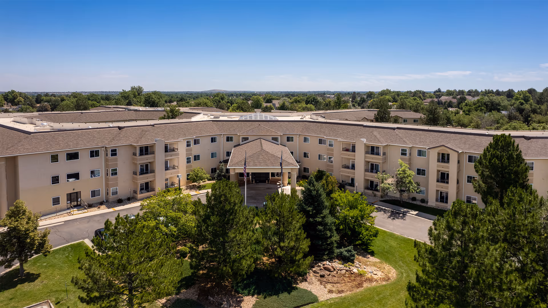 A U-shaped senior living facility exterior with a central entrance and landscaped grounds.