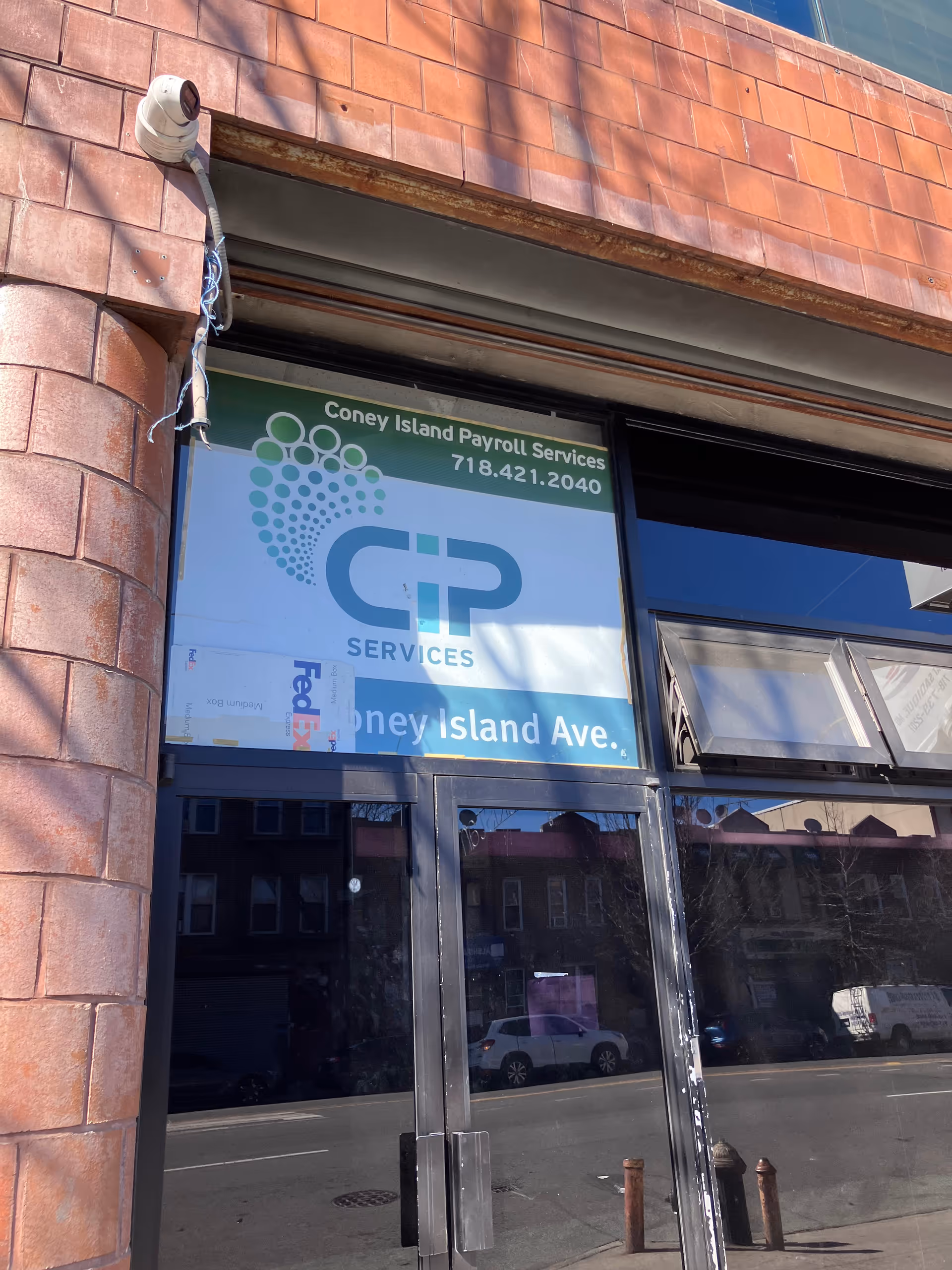 Brick building exterior with a large storefront window and a Coney Island Payroll Services sign.