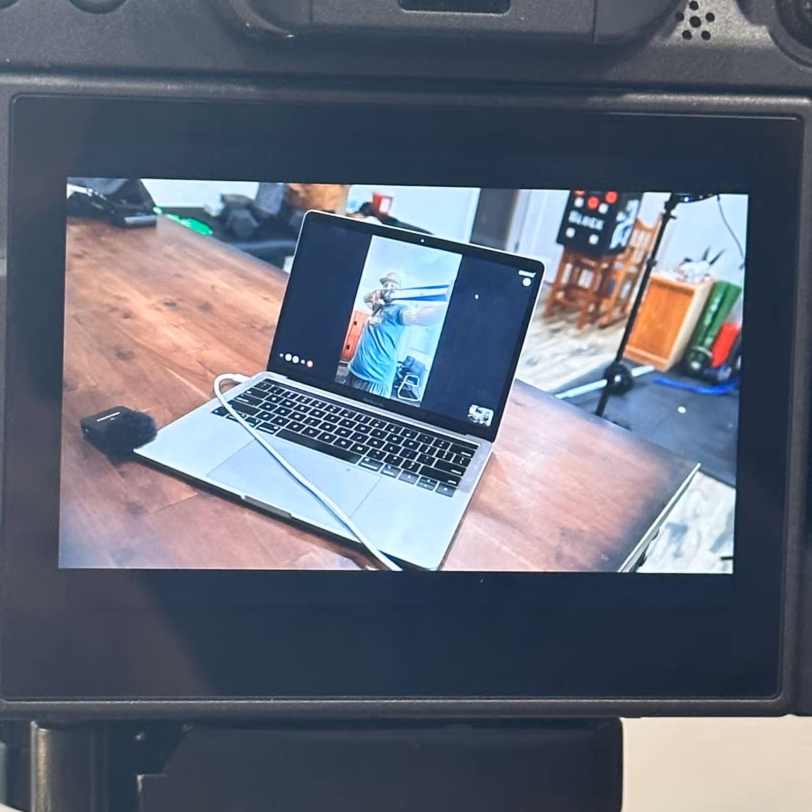 Camera preview showing a laptop on a wooden table with studio equipment in the background
