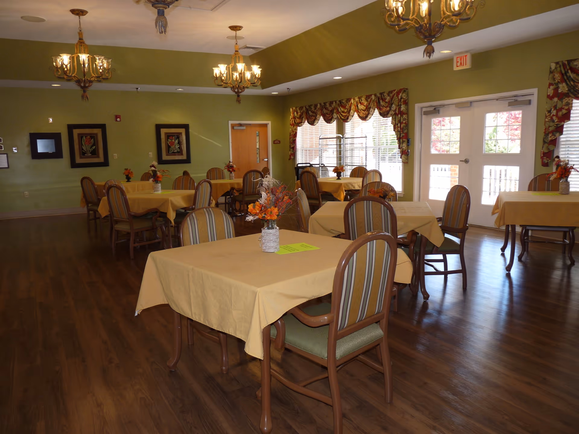 Senior living dining hall with yellow tablecloths, chairs, and centerpieces.