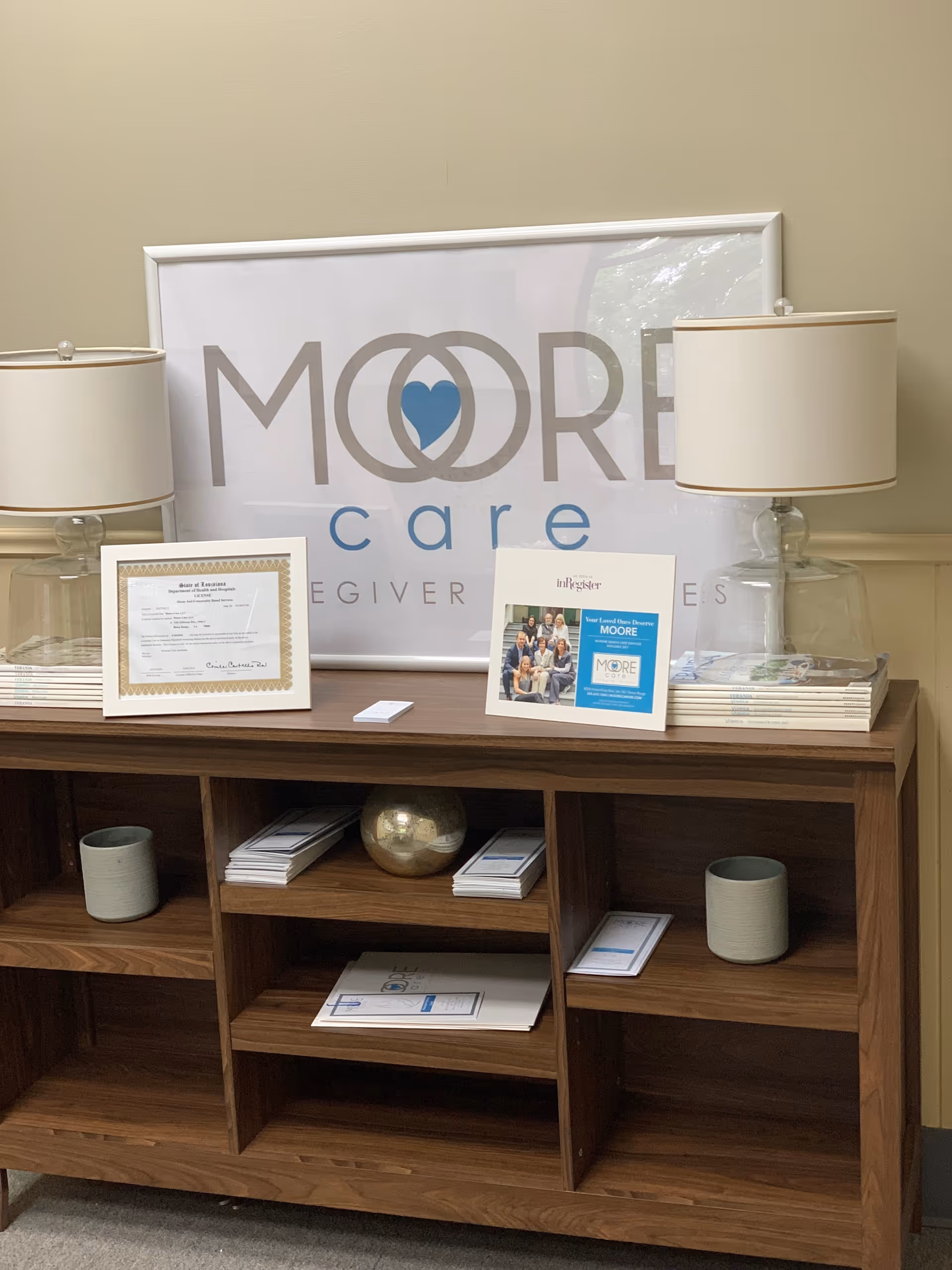 Moore Care sign behind a console with lamps, certificates, and brochures.