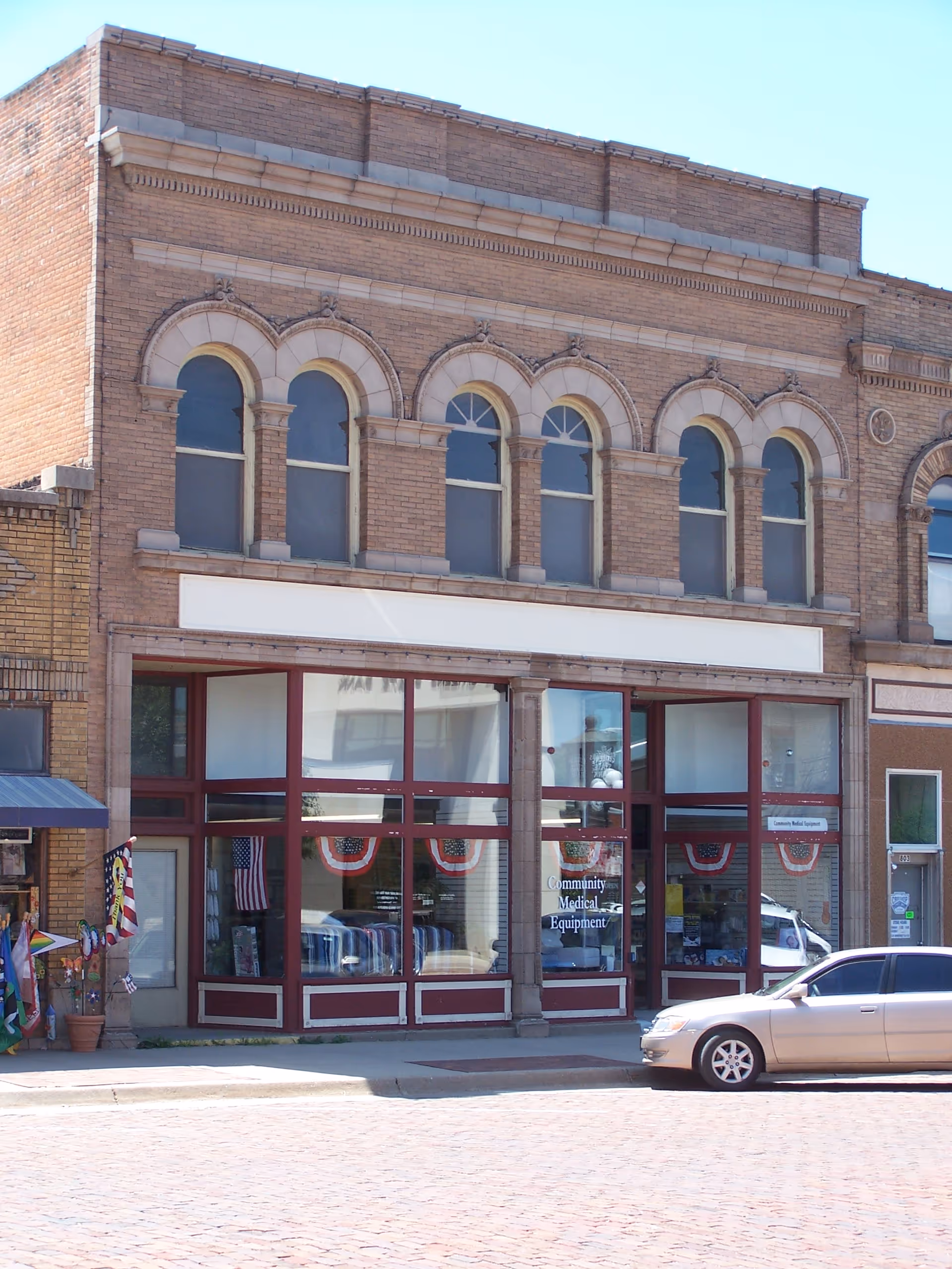 Brick storefront with large glass windows and a sign reading Community Medical Equipment.