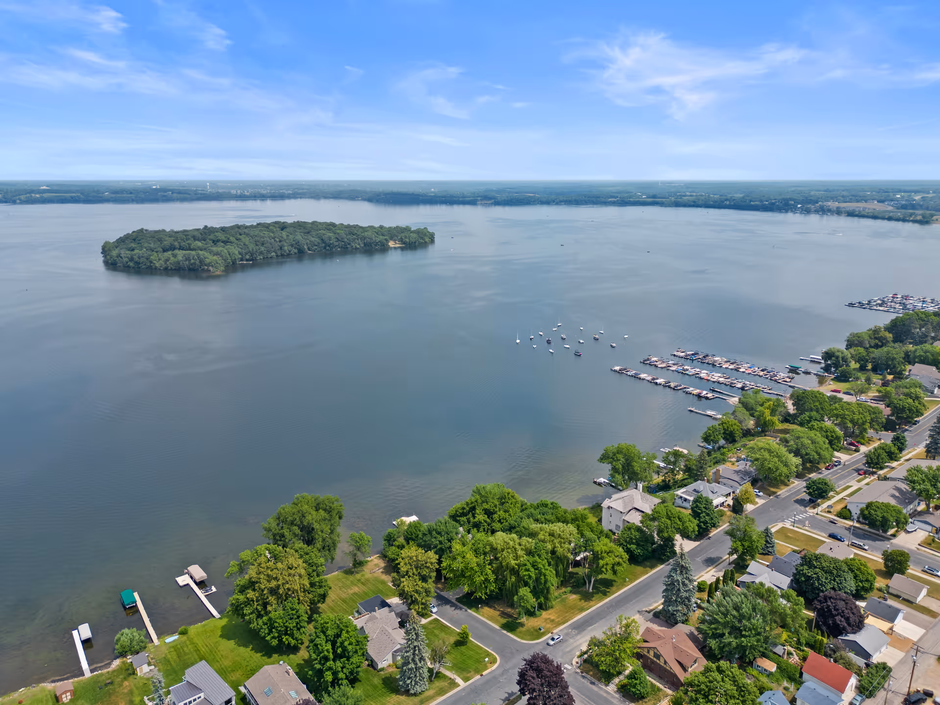 Aerial view of a lakeside community with houses, trees, and docks along the shoreline.