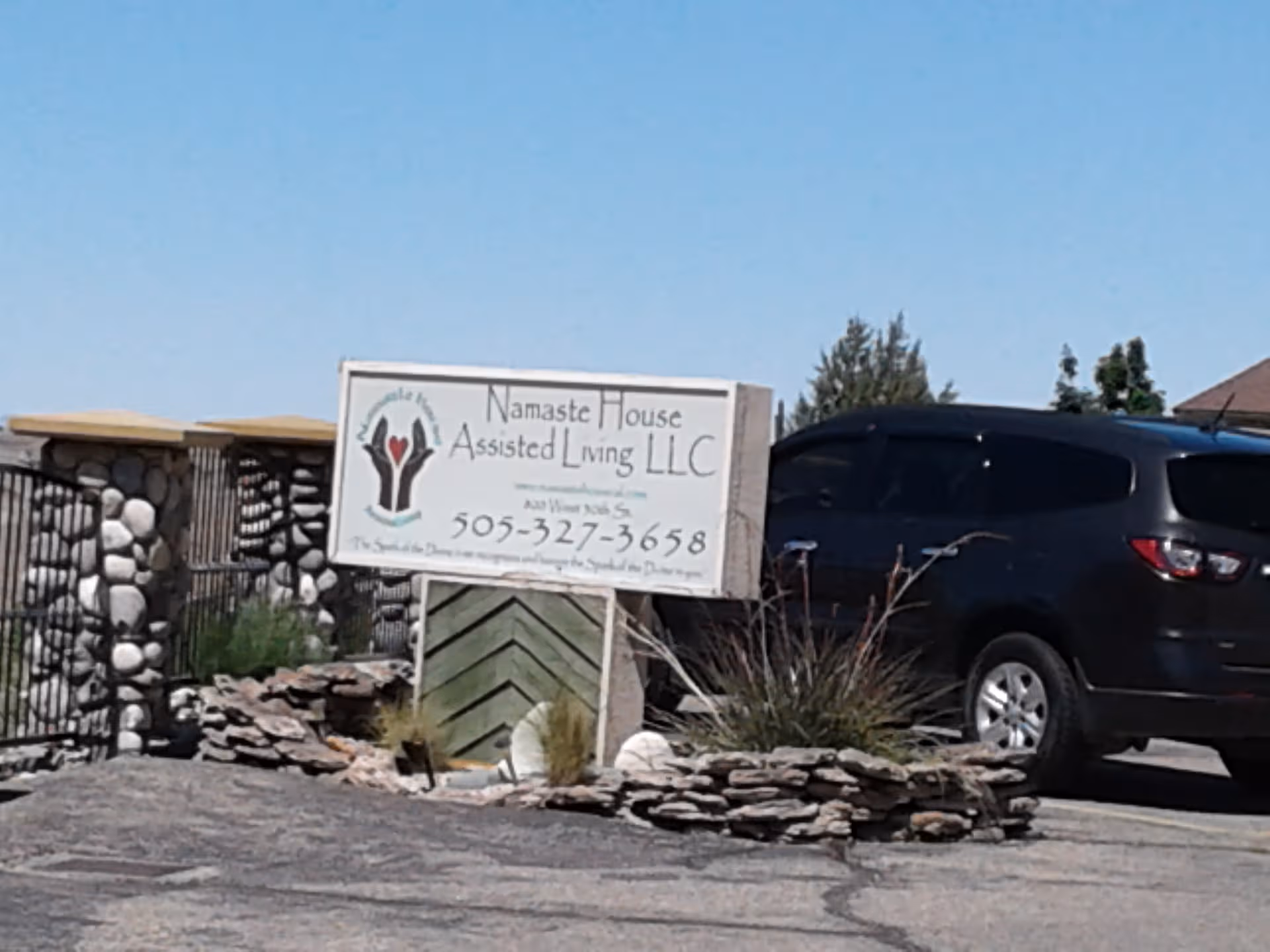 Front exterior view of Namaste House Assisted Living sign and parked black SUV.