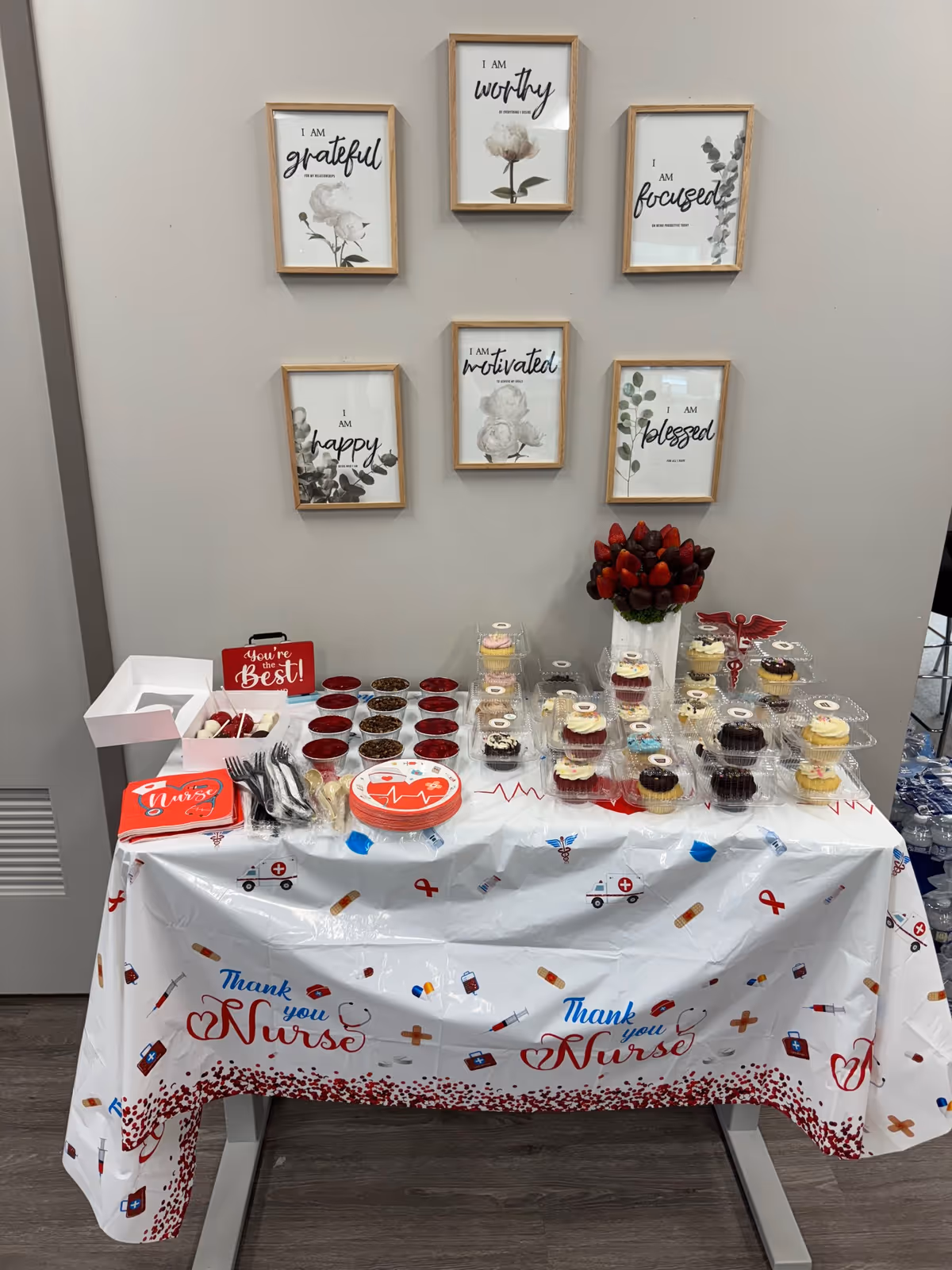 Interior scene with a nurse appreciation table featuring cupcakes and framed wall art.