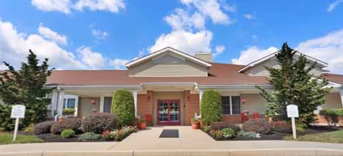 Front view of Brookdale Harrisburg building entrance with brick facade and landscaped shrubs.