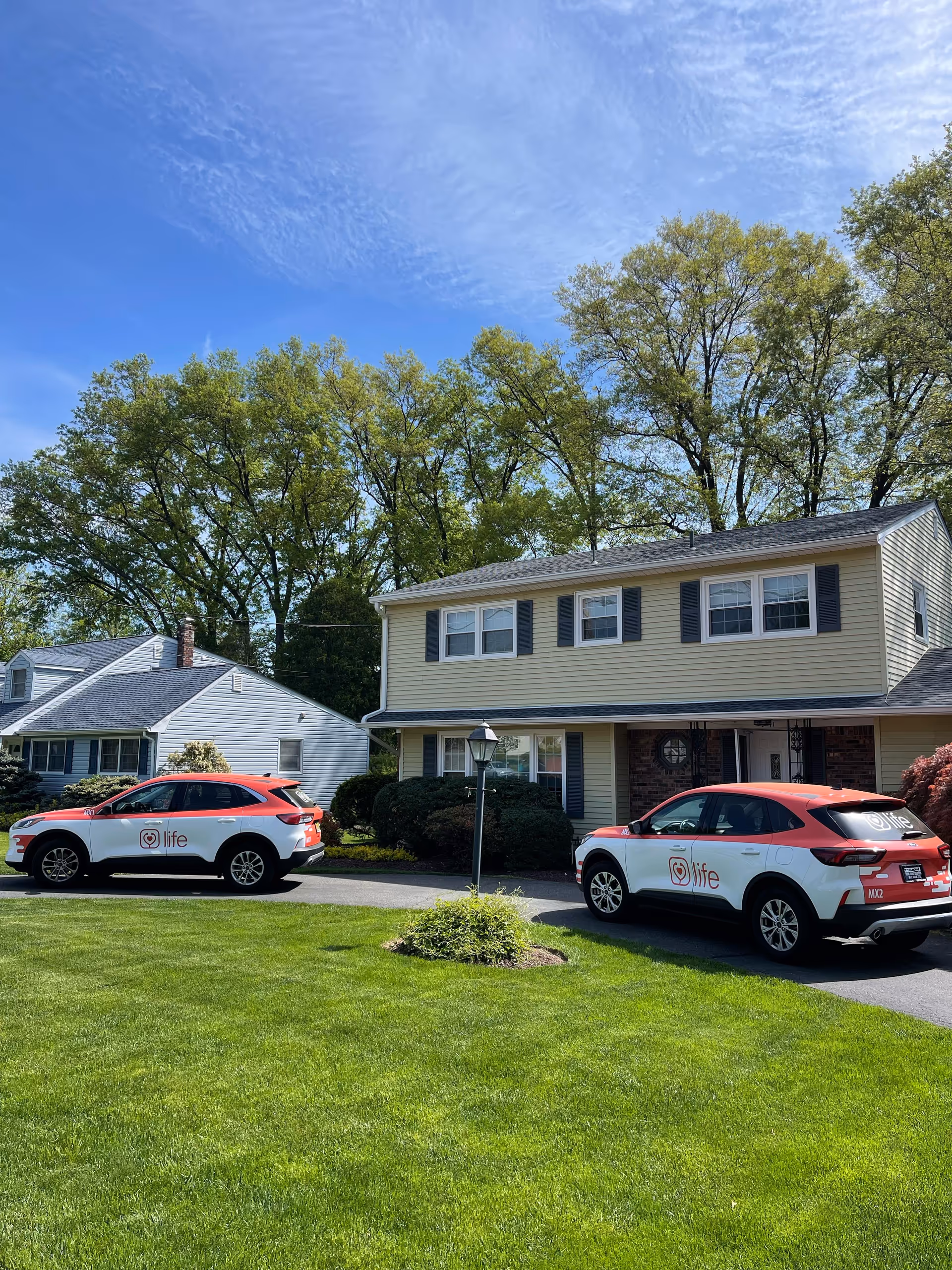 Two Life Medical branded cars parked in the driveway of a beige two-story house.