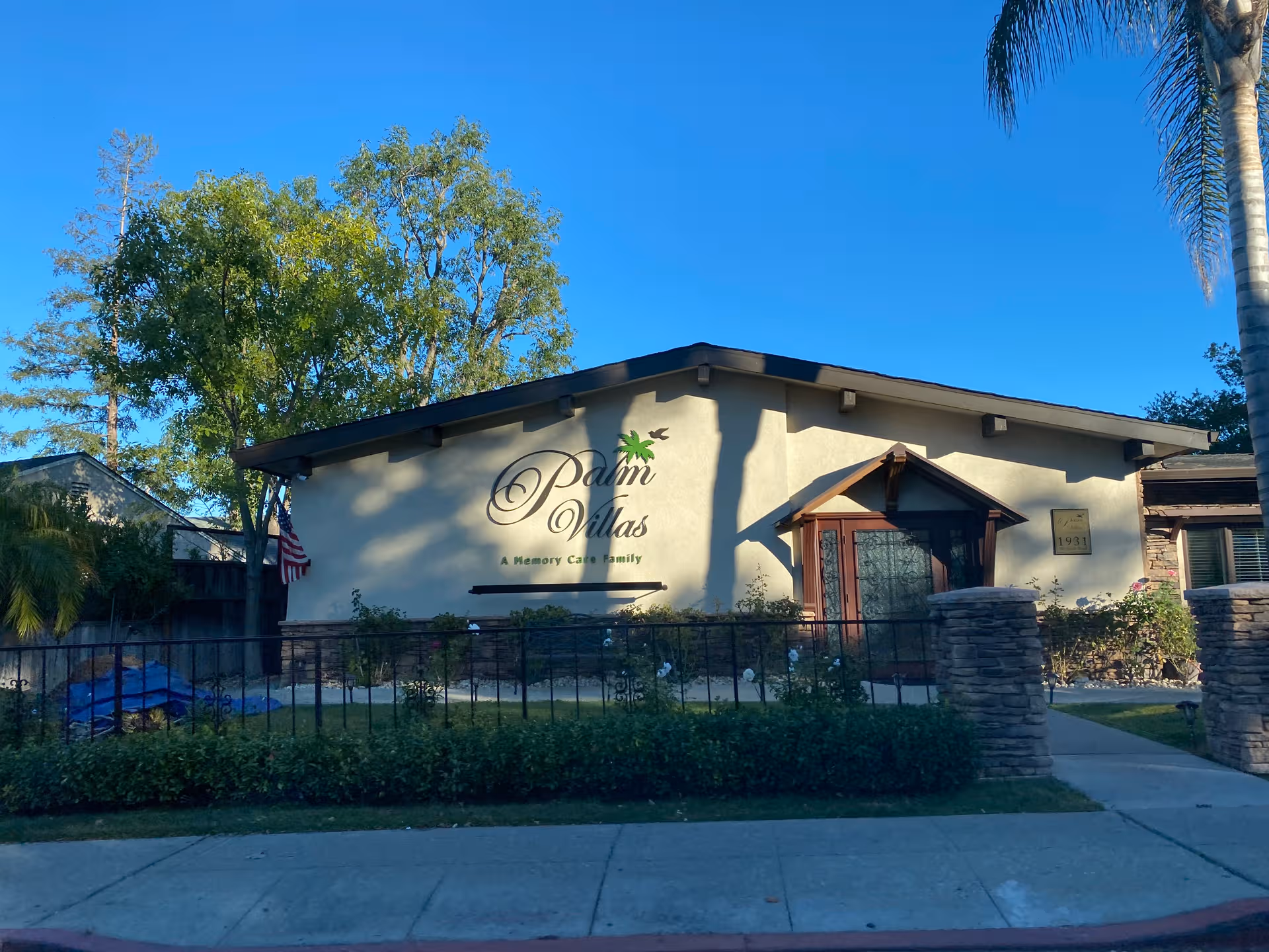 Front exterior of Palm Villas Memory Care building with entrance and landscaping.