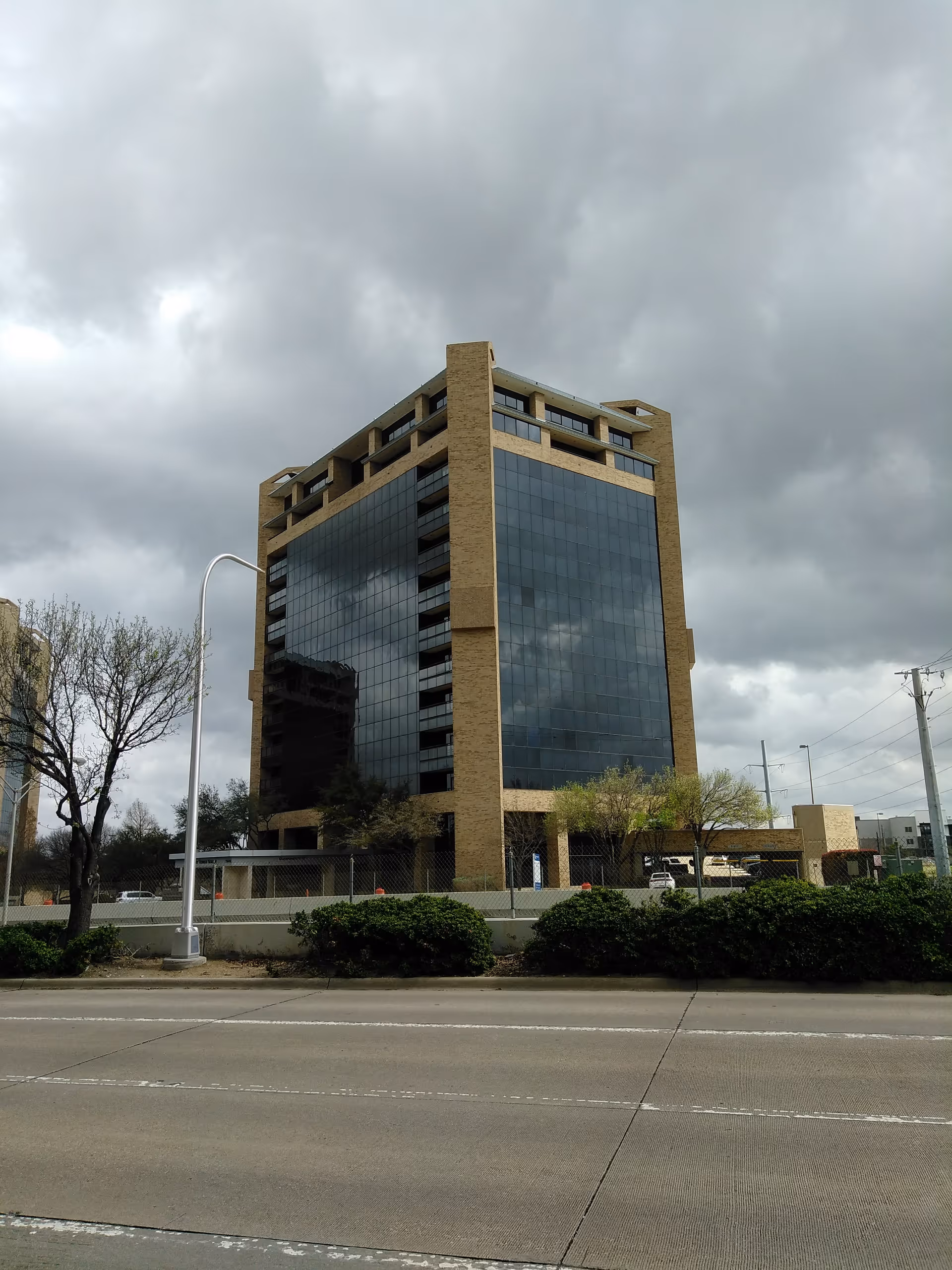 Exterior of a tall glass-and-brick building along a street.